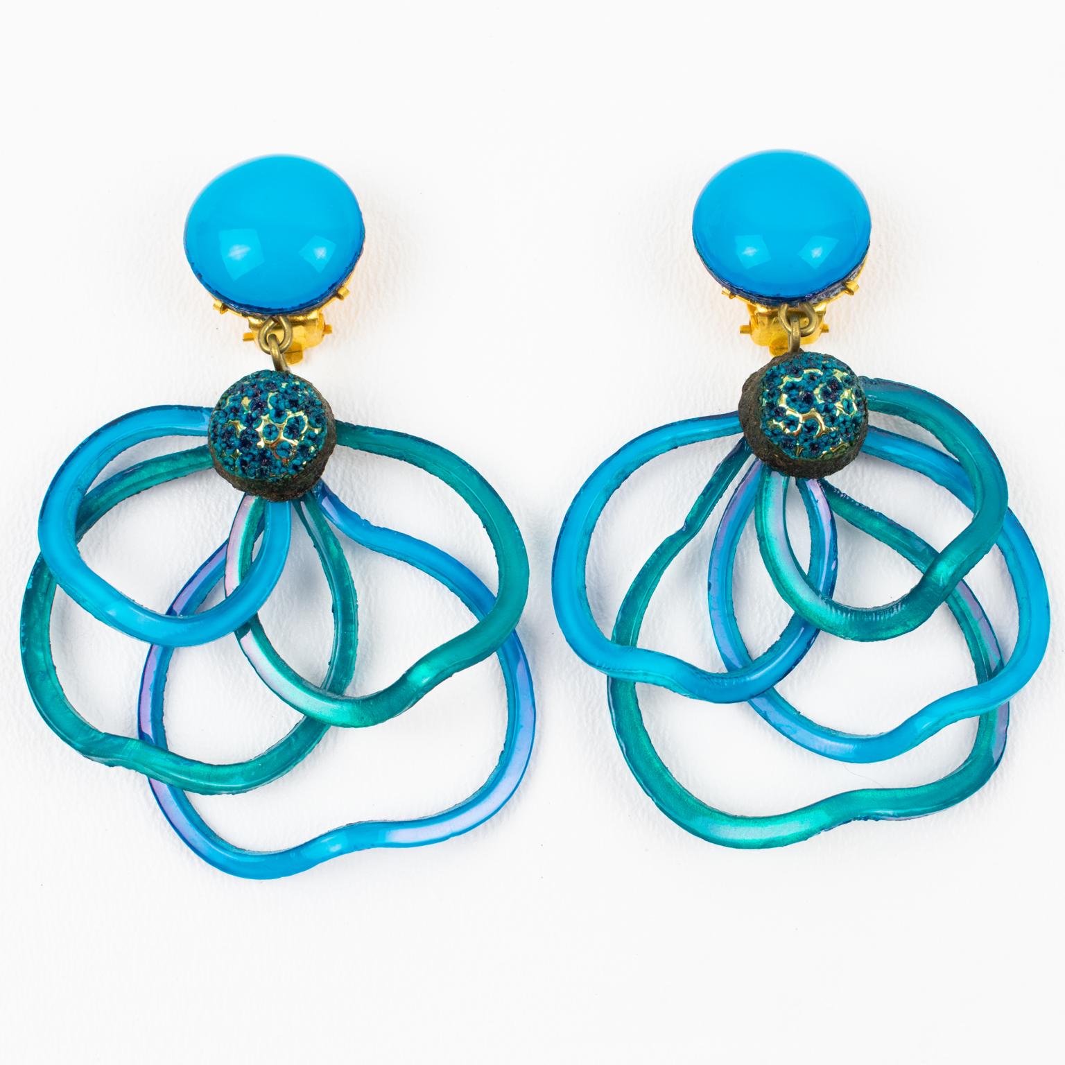 Cilea Paris created these stunning, dimensional dangling clip-on earrings. These artisanal resin earrings feature multi-loop arabesque ribbons with textured patterns that build together to form a powerful statement piece. The pieces boast a vivid