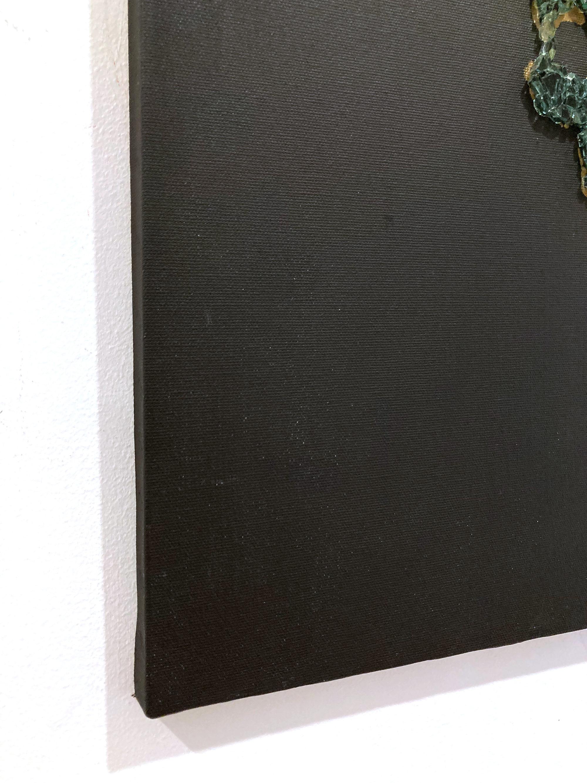 The painting features a dark black background with a textured, matte finish, giving it a deep, somber tone. Centered on the canvas is a skull-shaped form crafted with small broken green pieces of glass, arranged in a mosaic-like surface. With a