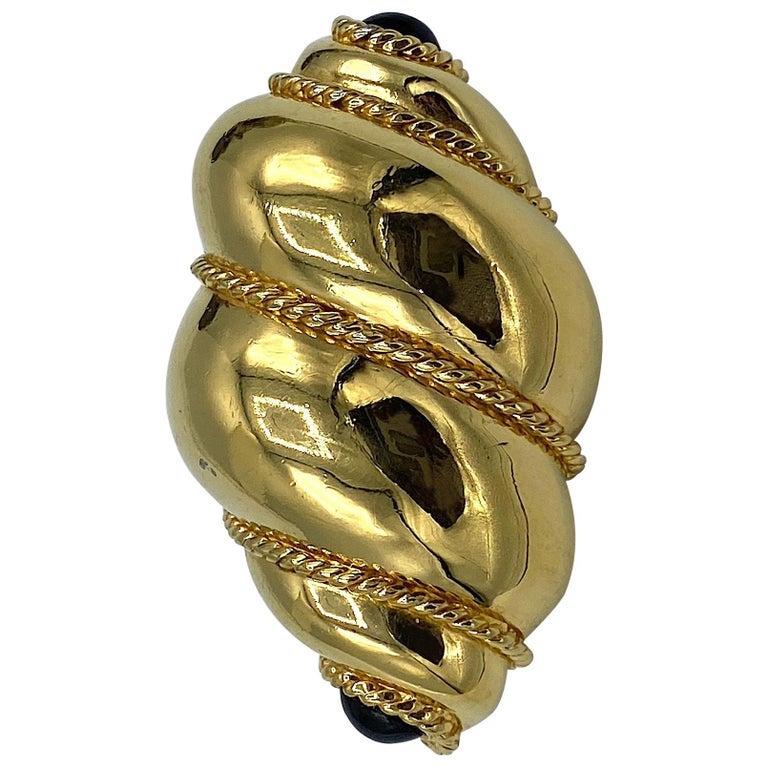 A lovely classic 1980s brooch by Ciner. The piece is cast in a three dimensional spiral or twist design in smooth gold plate with thin rope design in the crevices for contrast. The top and bottom of the brooch is set with oval black glass cabochons.