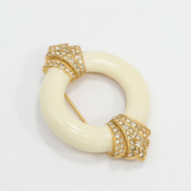 Art-deco style pin brooch by American-based designer Ciner. Round cream-enamel motif decorated with crystals set in gold accents.

Gold-plated

Marks / hallmarks / etc: Ciner