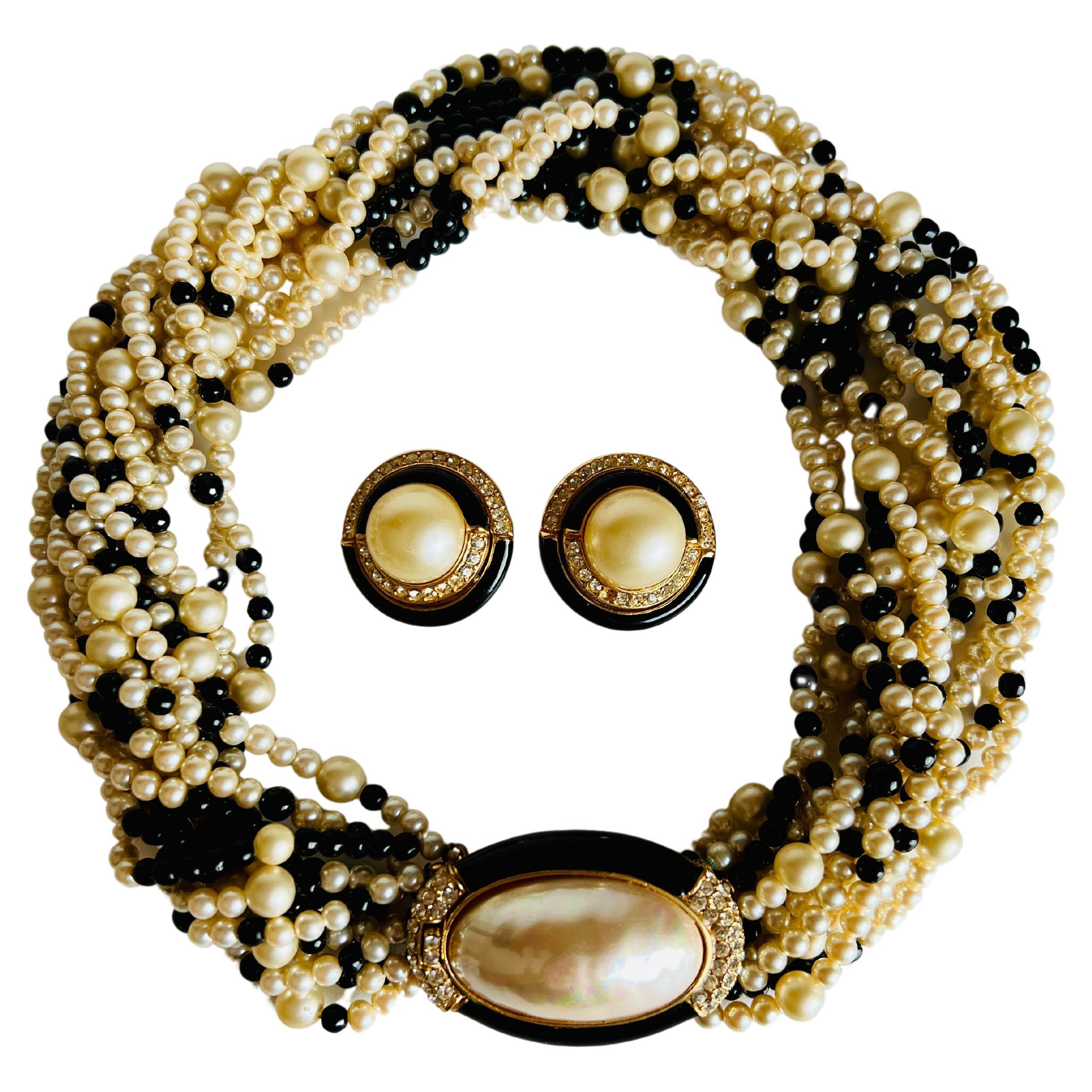 This elegant set includes an imitation pearl, black glass torsade necklace featuring a gold-tone clasp centering an imitation mabe-style pearl highlighted with rhinestones and black enamel together with a pair of matching clip on earrings.

Size: