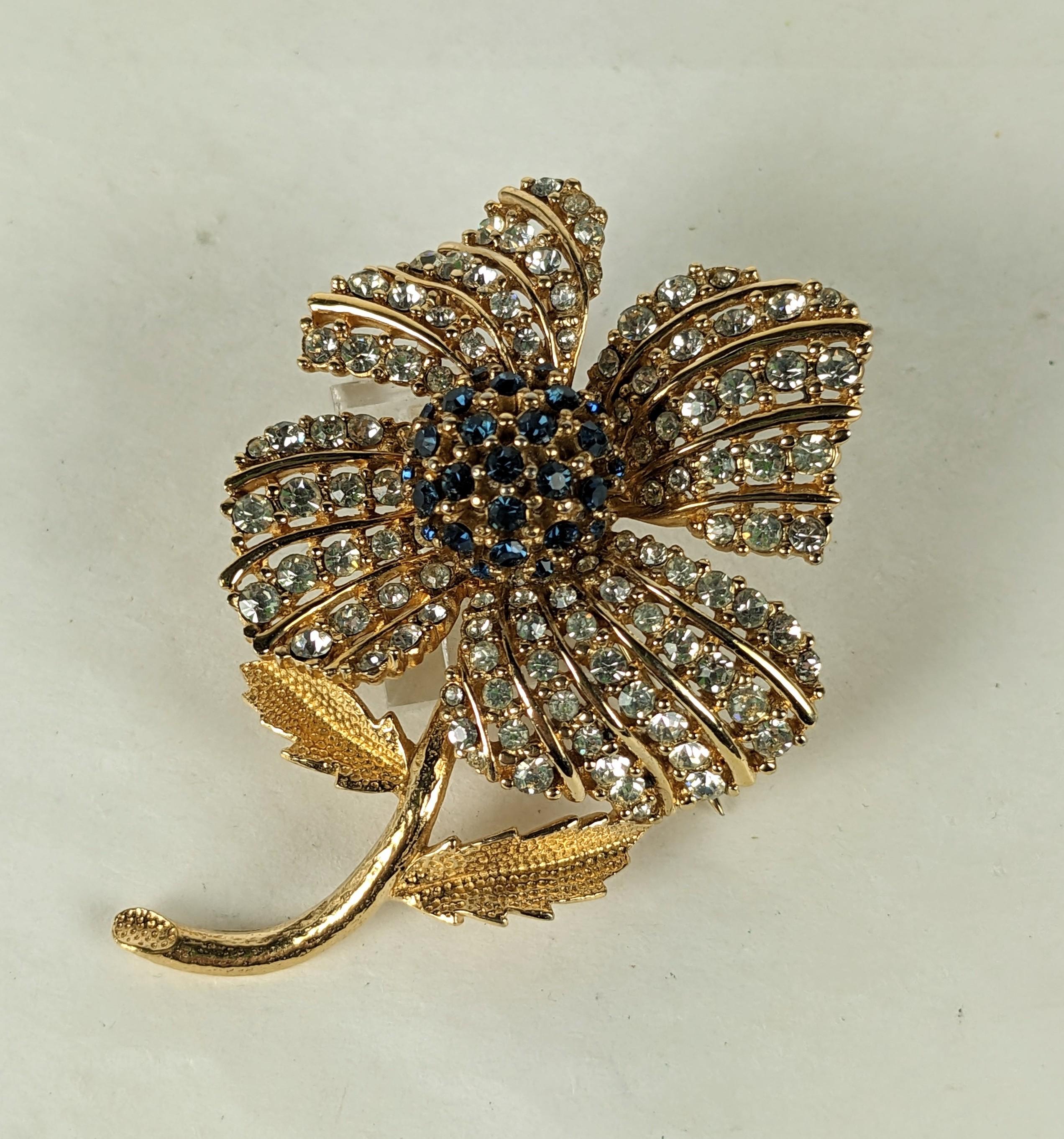 Charmante broche en forme de fleur Ciner des années 1960. Travail de pavage élaboré avec des pétales en cristal et un bouton central en faux saphir sur métal doré. 
2.5
