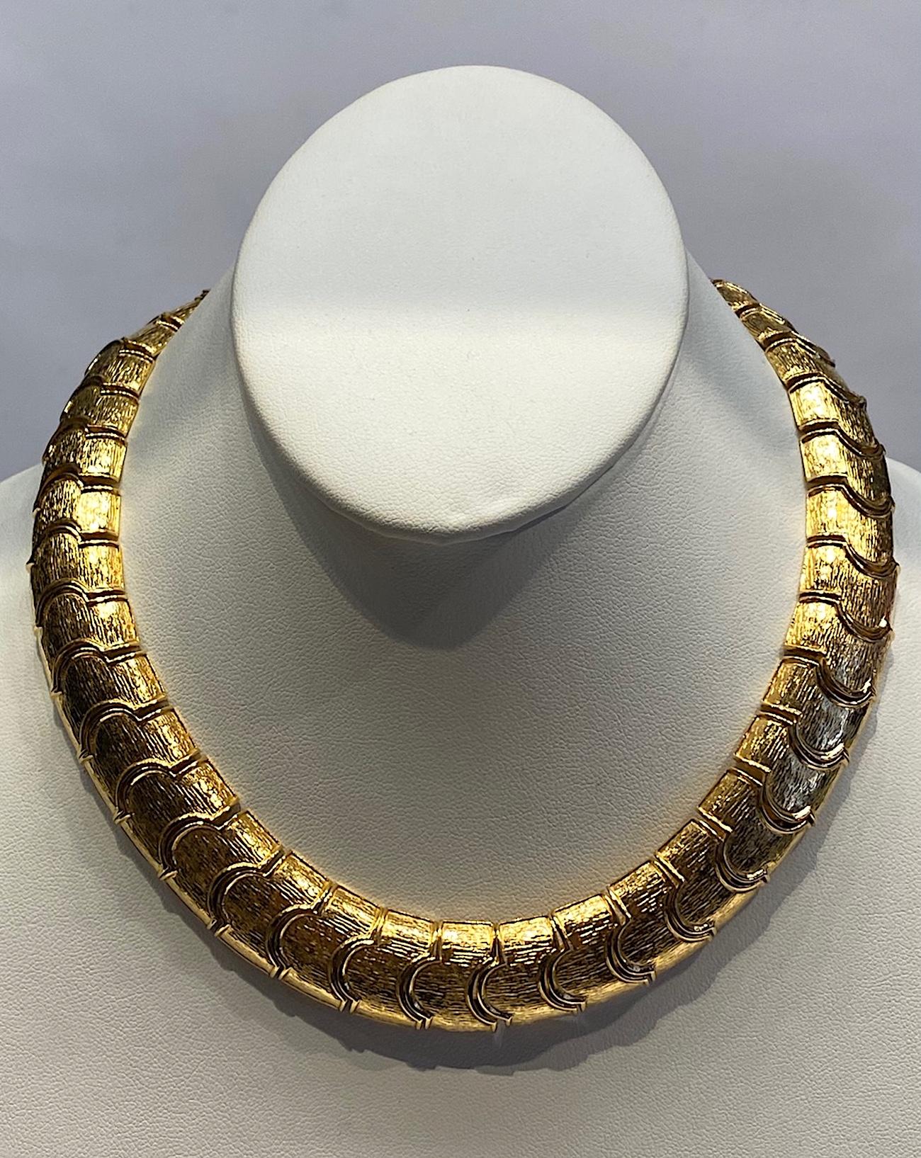 A lovely tailored style 1980s necklace by American fashion jewelry company Ciner of New York. There are 41 lightly textured parenthesis shape links that make up the necklace. It is .75 of an inch wide and 16.5 inches long. The push pin clasp is