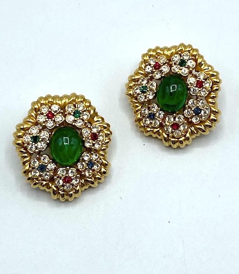 A stunning pair of  medallion button earrings in the Mughal style by New York fashion jewelry company Ciner. The earrings are beautifully cast with a ribbed or scalloped edge. The center is set with a large oval faux glass emerald with inclusions