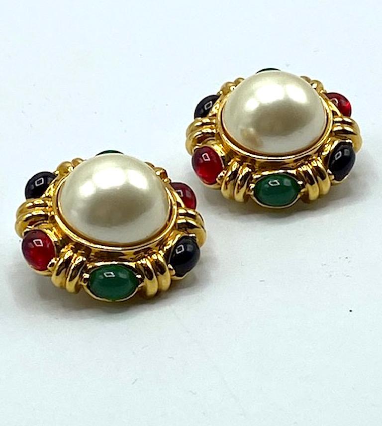 A stunning pair of large button earrings in the Mughal style by New York fashion jewelry company Ciner. A large central faux pearl cabochon is set into a cast gold plate setting and complimented by surround red, blue and green oval glass cabochons.