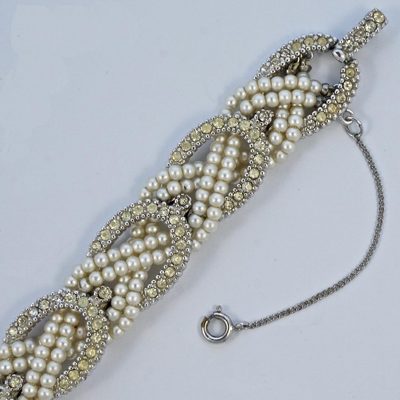 Fabuleux bracelet Ciner en métal argenté avec une chaîne de sécurité, comportant deux rangées de fausses perles ivoires et des liens en strass. Longueur 19.2cm / 7.5 inches et largeur 1.5cm / .6 inch. Le bracelet est en très bon état.

Il s'agit