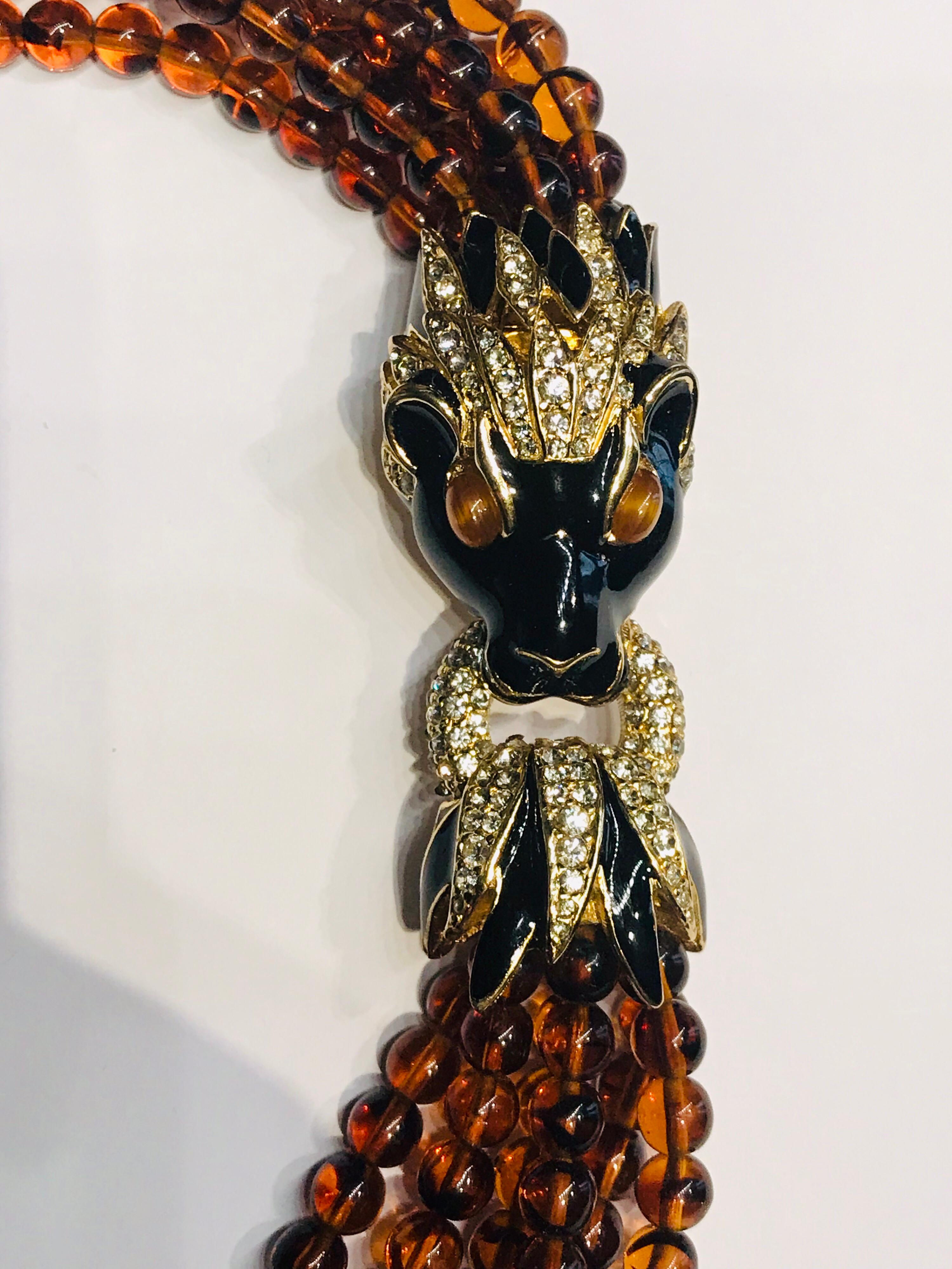Beautiful Ciner tornado necklace from the 1980s. The necklace has six strands of 5 mm faux amber glass beads and a Lion head and ring clasp. The clasp is black enamel, gold plate and Swarovski crystal rhinestone. In the mane of the lion head is a