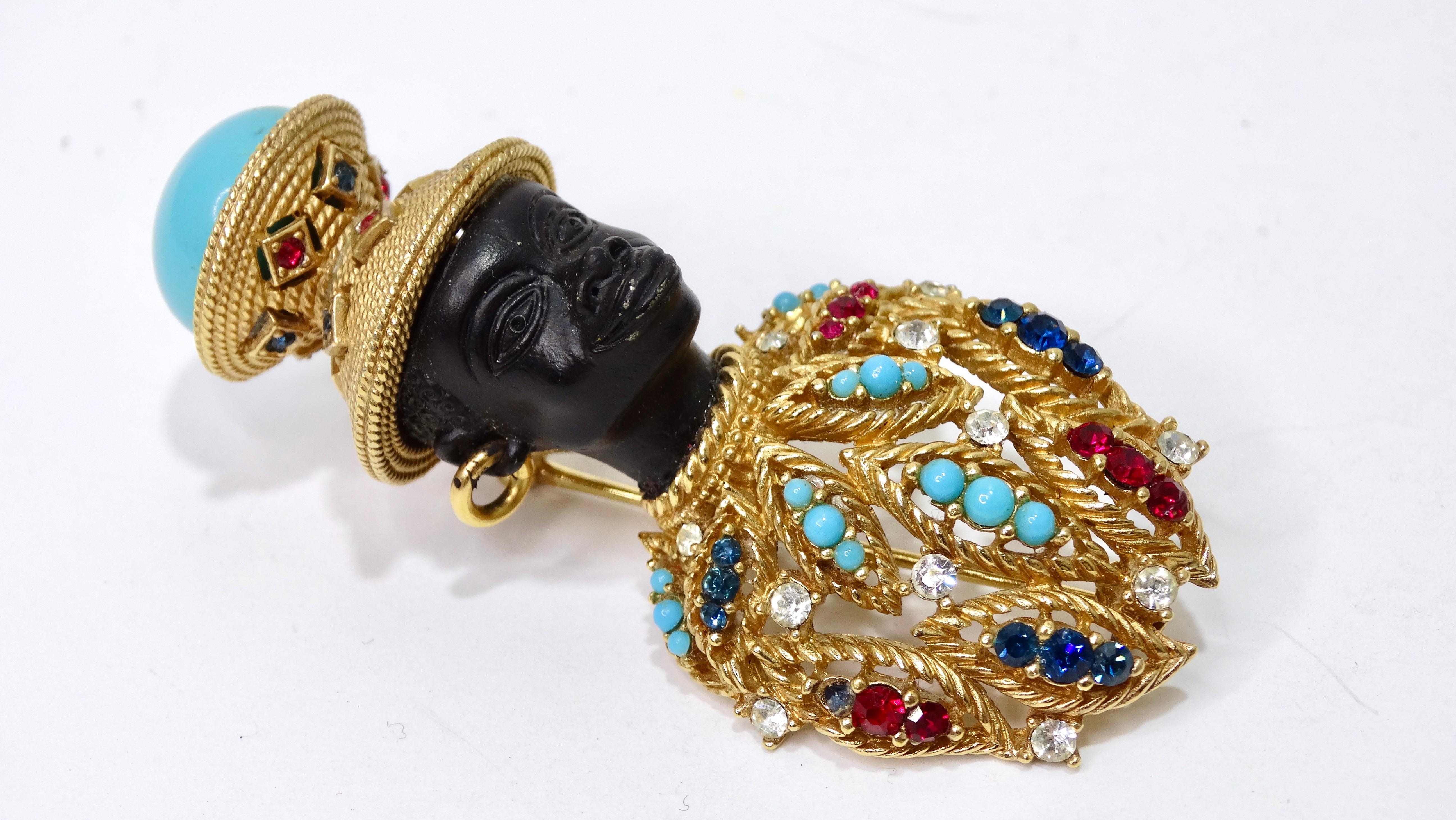 This piece is a stunningly detailed brooch! A beautiful vintage 1960s Venetian style Nubian brooch features gold-tone mounting, with faux carved head with gold-tone hoop earrings, large blue bead, and rhinestone jeweled front. Signed Ciner on the