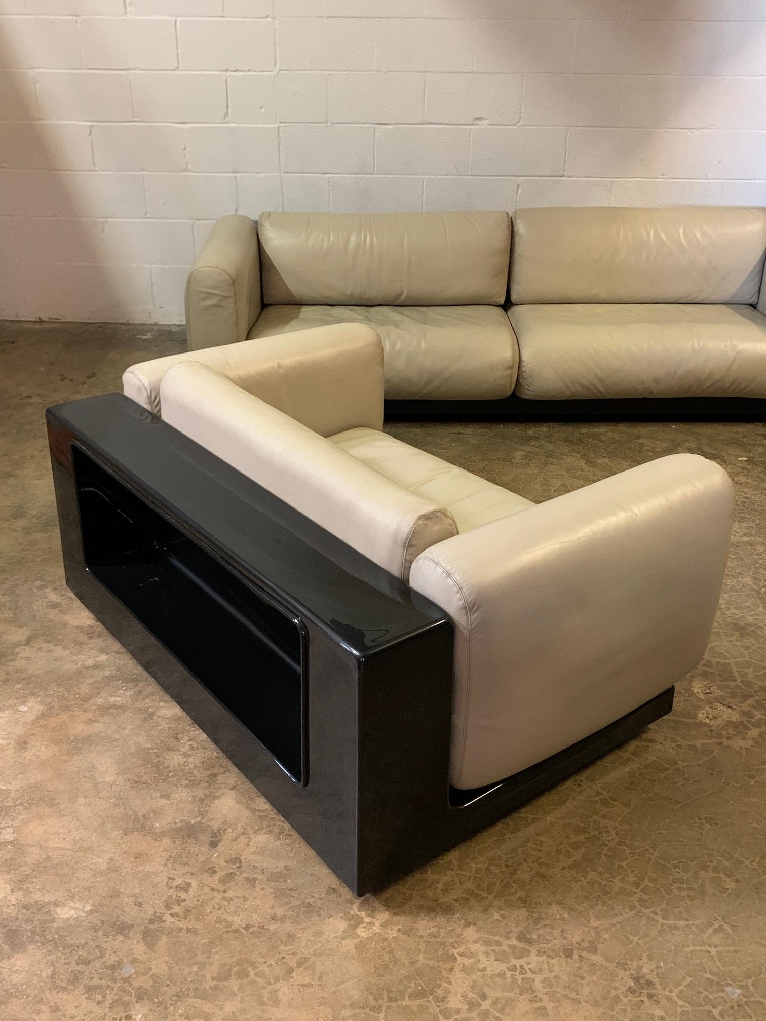 Part of the 'Gradual' seating system designed by Cici Boeri and sold through Gavina / Knoll in 1971. This settee has a dark brown fiberglass frame with intergraded shelf and casters. The original cream colored leather is supple and has a nice even