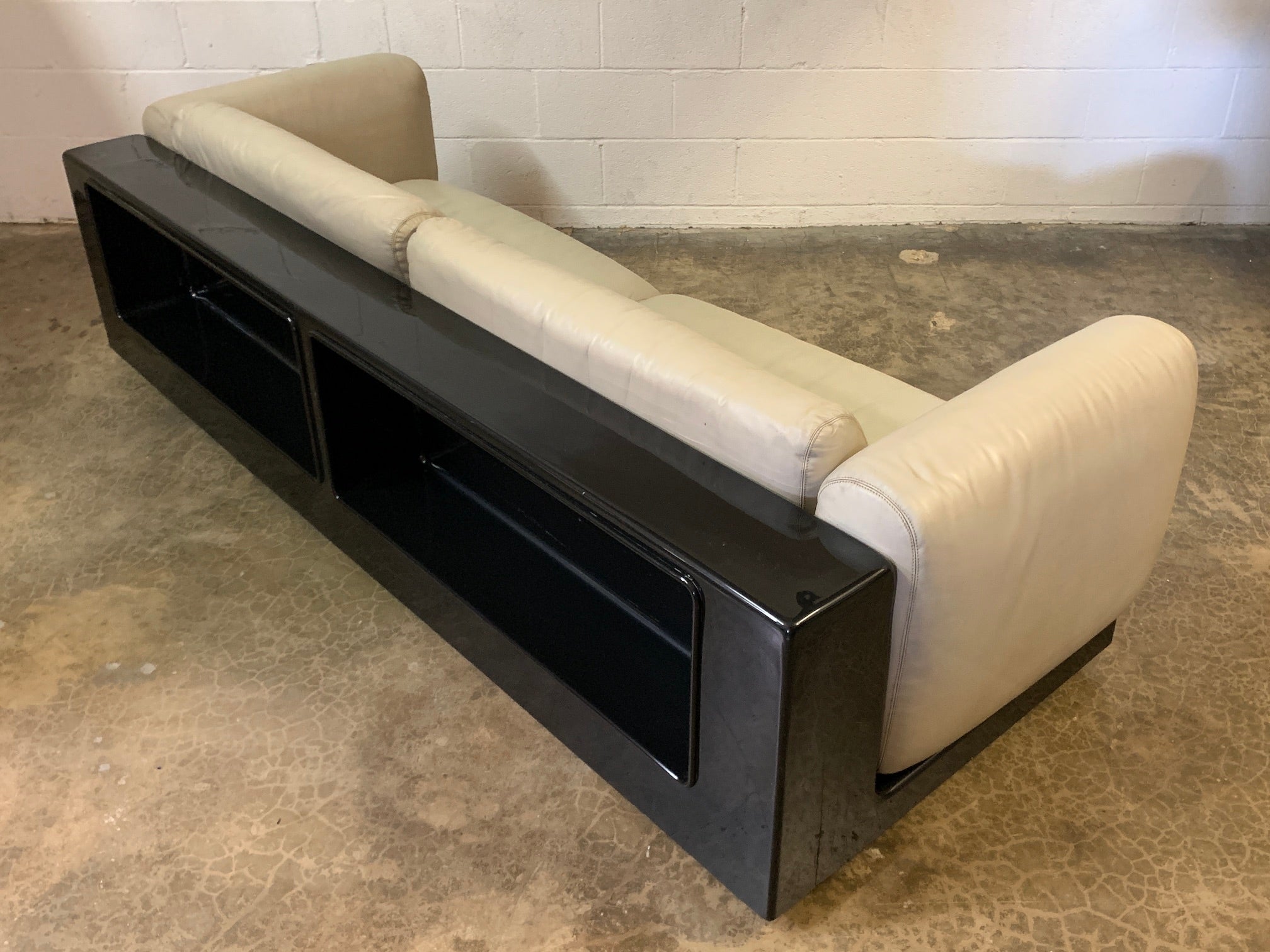 Part of the 'Gradual' seating system designed by Cici Boeri and sold through Gavina / Knoll in 1971. This sofa has a dark brown fiberglass frame with intergraded shelf and casters. The original cream colored leather is supple and has a nice even
