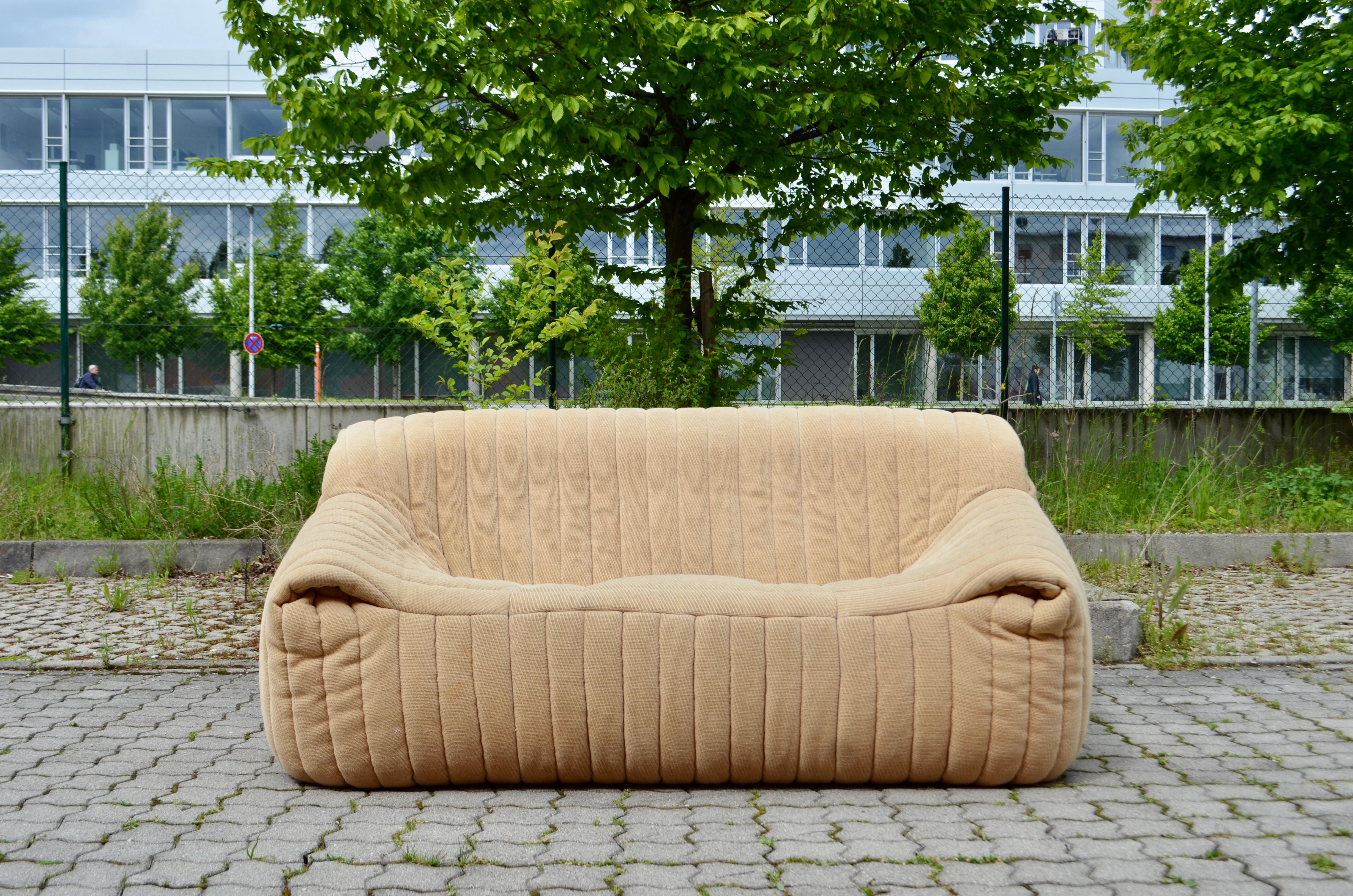 Cinna / Ligne Roset modèle Sandra conçu par Annie Hieronimus.
Il s'agit de la version 2 places.
Le tissu présente un motif à rayures, un modèle typique des années 1970.
Le tissu est une structure de velours écru brillant et il a quelques petites