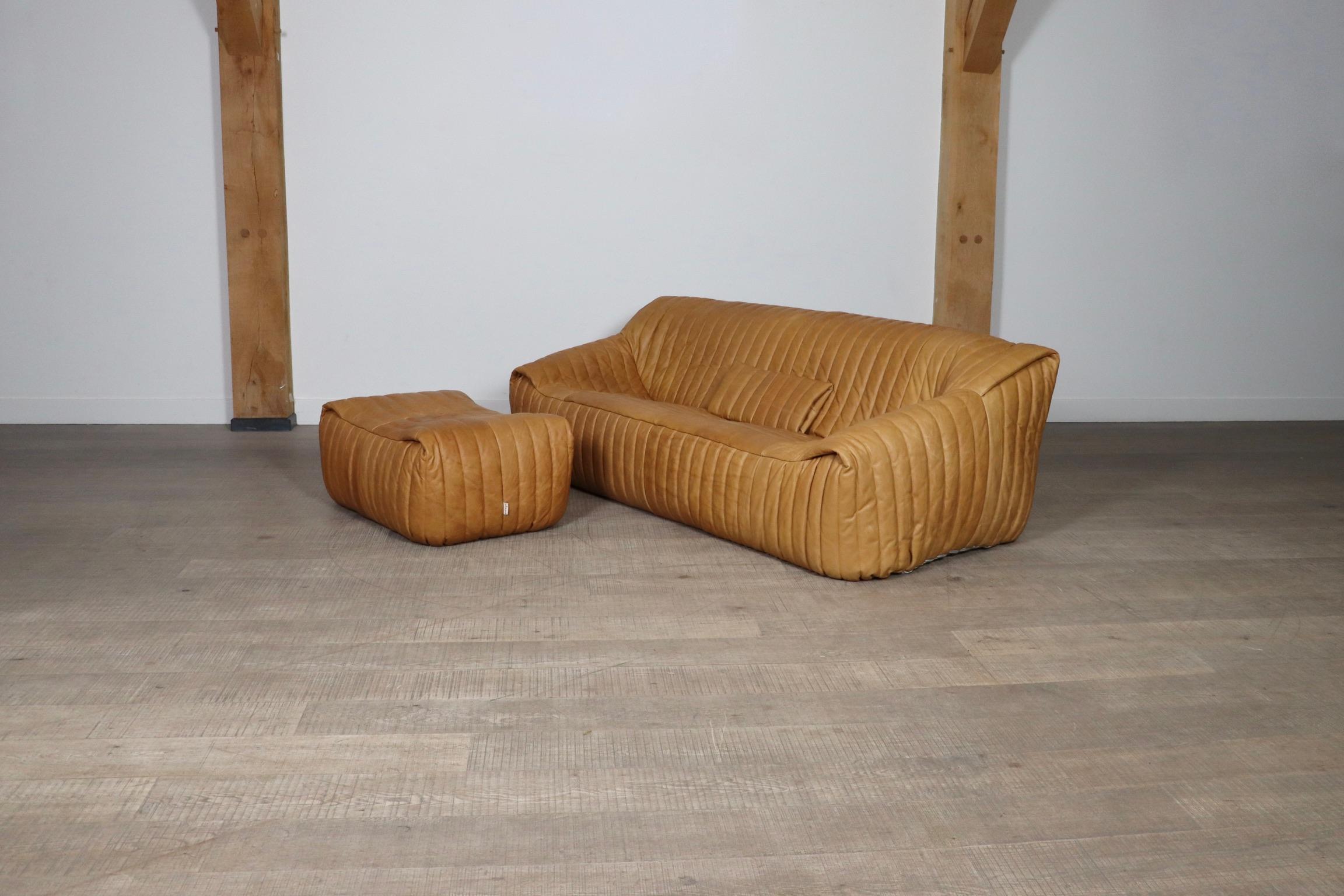 Beautiful three seater sofa with ottoman in stunning tan leather, by Annie Hieronimus for Cinna, a division of Ligne Roset, France 1970s. This incredibly comfortable, yet lightweight design will instantly bring character to any room! Reupholstered