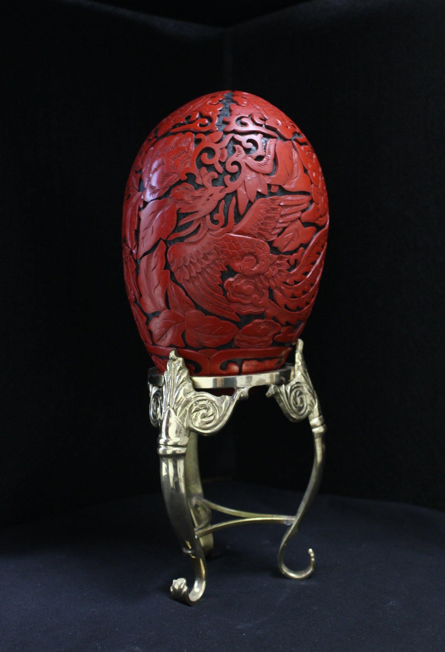 The finely-carved, sinuous, five-clawed dragon exhaling a fireball, and the phoenix with long, billowing tail feathers are both flying amid blossoming peony flowers and leaves. 

The bottom is adorned with giant bird of paradise leaves, and the top