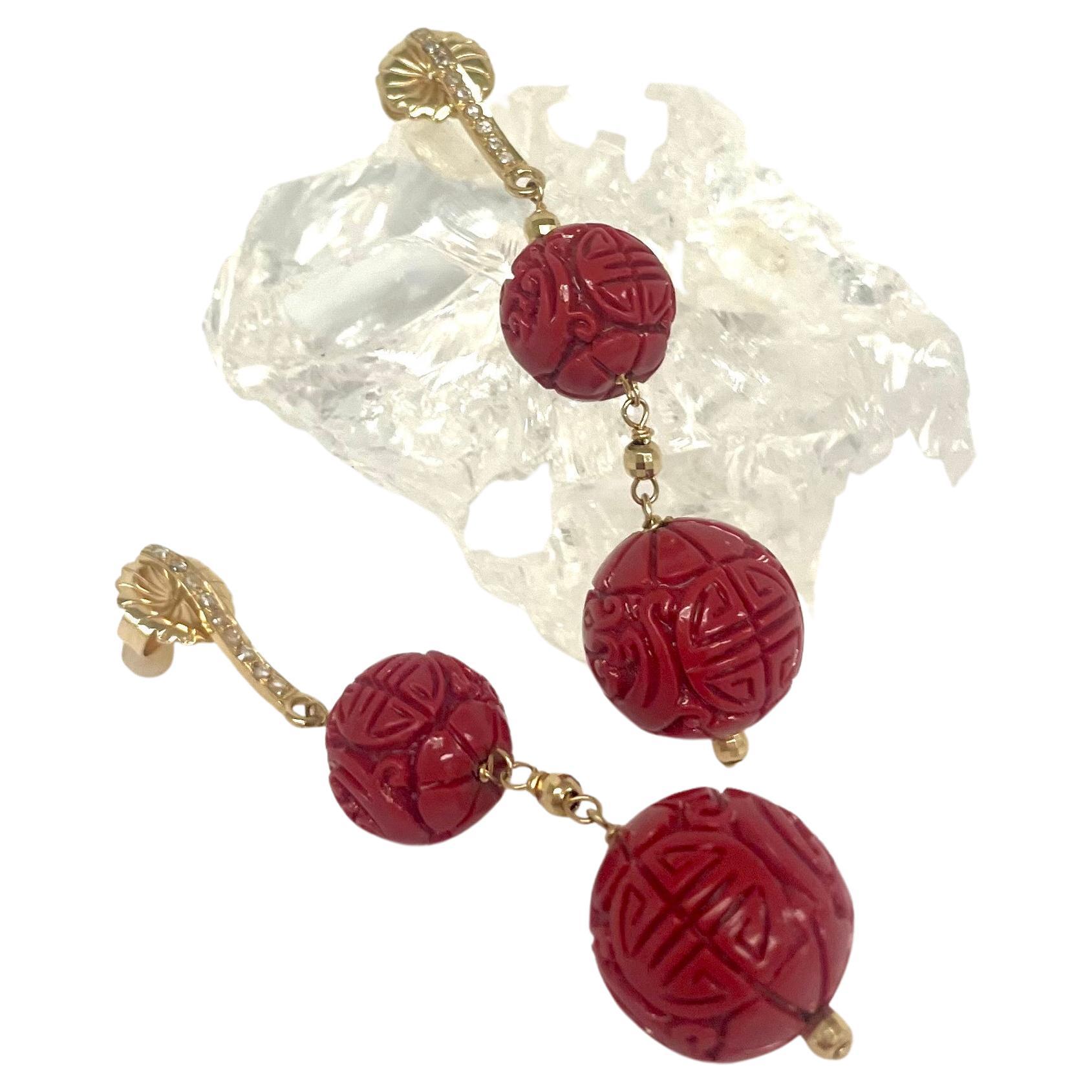 Description
Striking, vibrant, beautifully carved cinnabar red balls accented with 14k yellow gold faceted beads and suspended from pave diamond wavy bar posts to create a unique harmonized two drop style earring.
Item # E3365

Materials and
