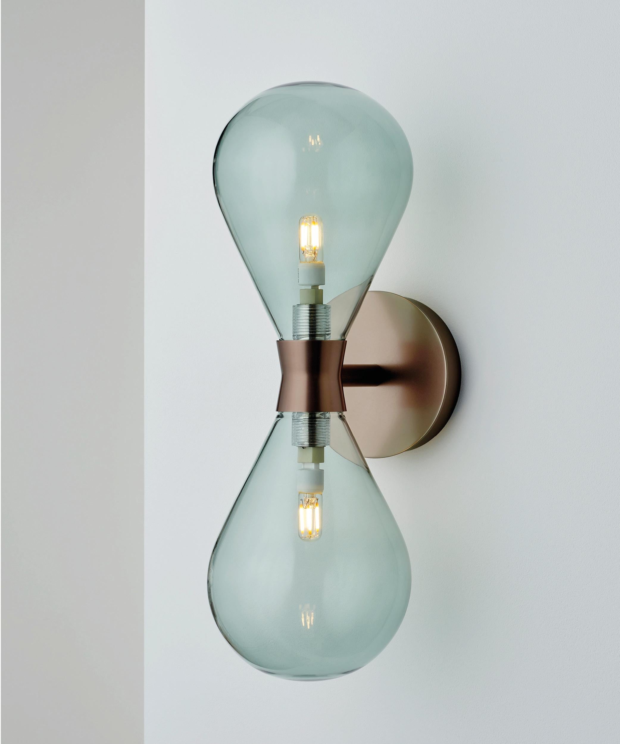 A larger version of the Cintola Wall Light, the Twin adds vertical height and presence to the rounded profile of its sibling. Available in a range of standard and custom finishes, alongside a selection of complementary glass colours.

Custom finish
