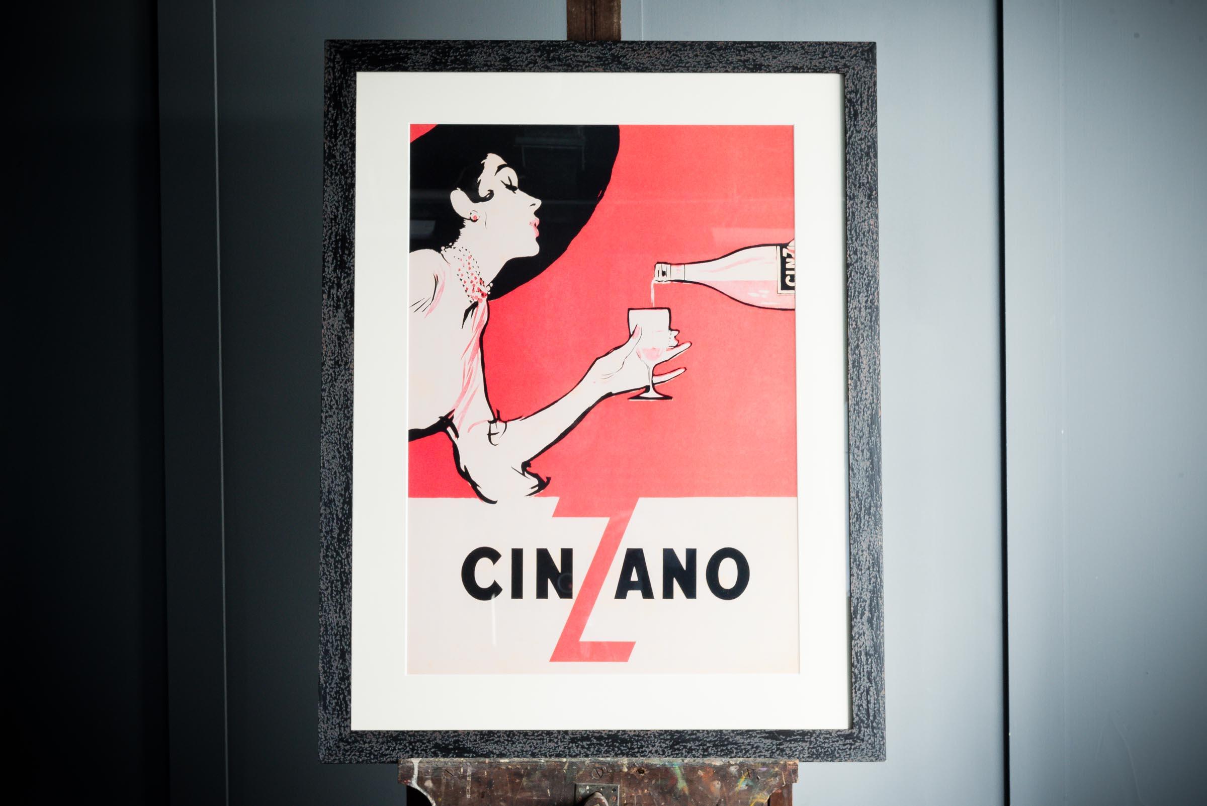 1950's advertising poster showcasing the alcoholic beverage Cinzano. The poster comes in a black wooden frame.