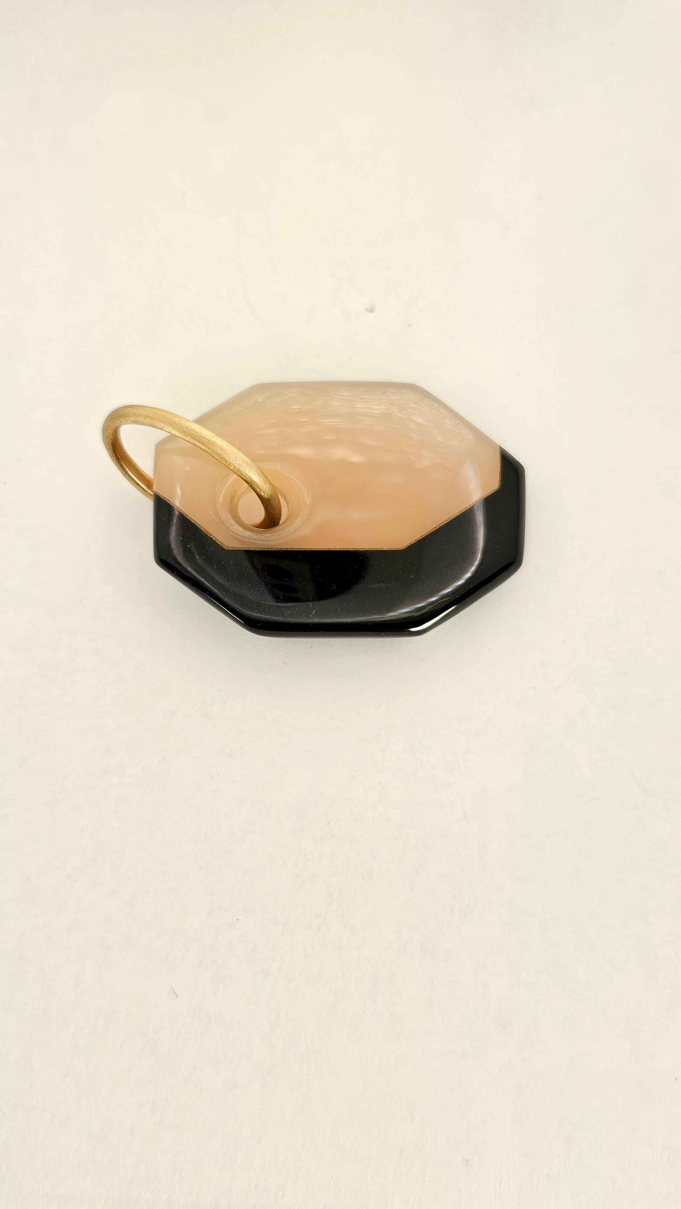 Un ciondolo dalla forma ottagonale allungata dal design geometrico.
L'originalità di questo pendente sta nella sua costruzione. Viene realizzato infatti, tagliando le due pietre precisamente ad incastro in modo che possano essere unite e