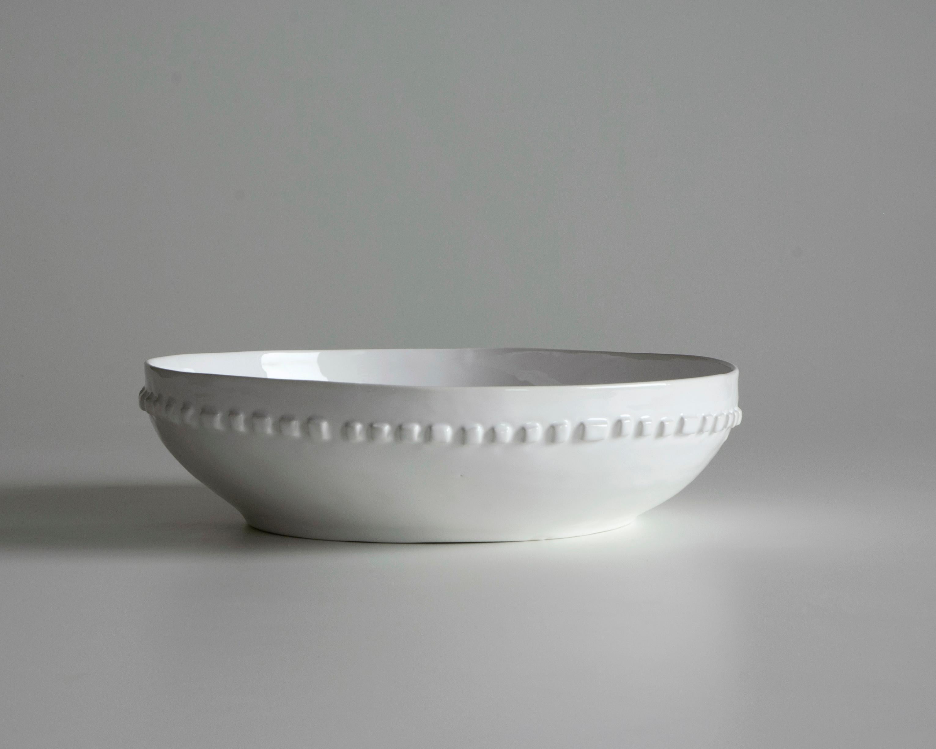 The white ceramic bowl has a relief decoration. Each small piece is made by hand, giving each a unique character. The enameling applied using the dipping technique, with its subtle imperfections, gives the piece a distinctive and authentic appeal.