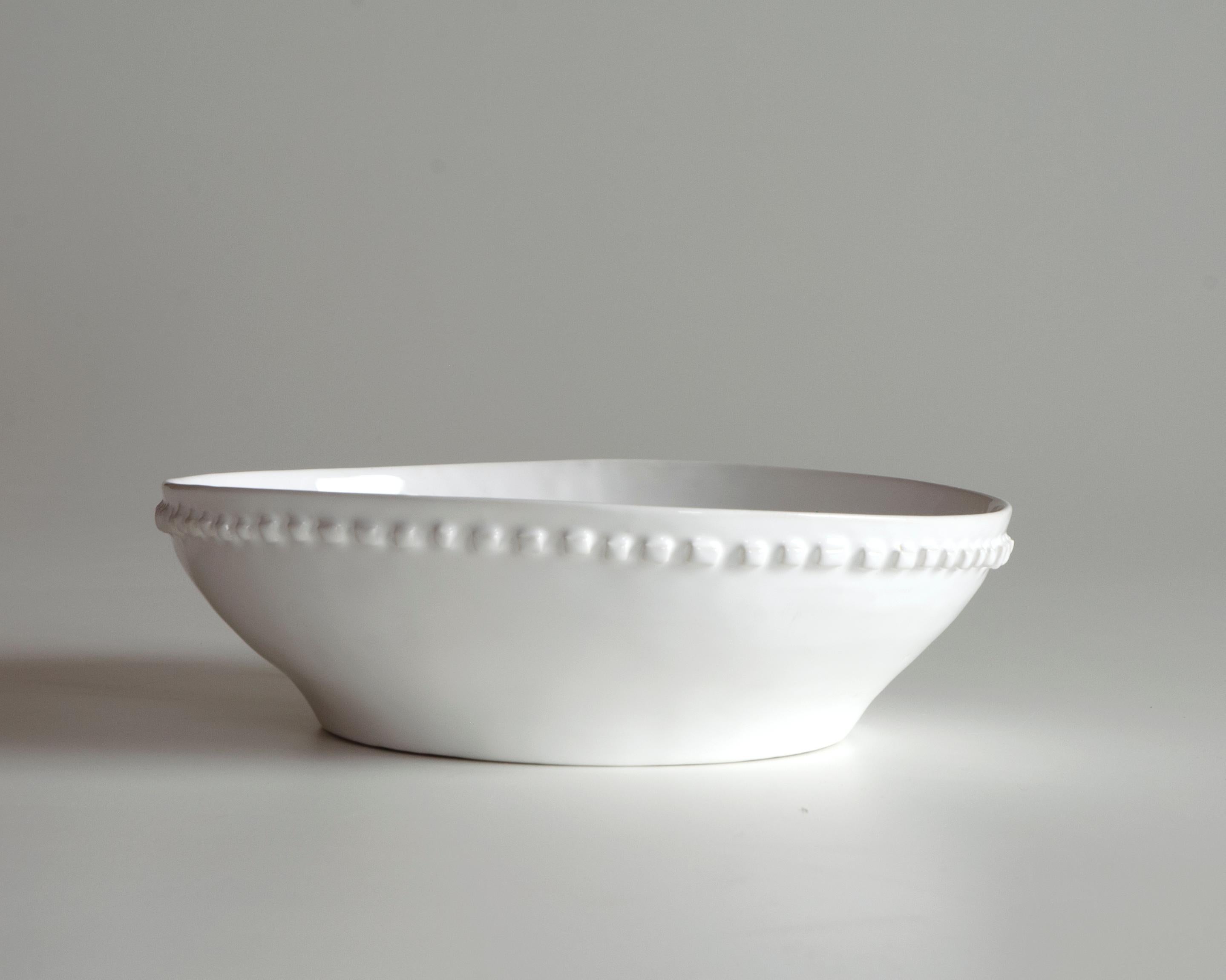 La ciotola in ceramica bianca ha una decorazione a rilievo. Jeder kleine Quast wird von Hand gefertigt und verleiht jedem einen einzigartigen Charakter. Die mit der Technik des Eintauchens angewendete Glätte mit ihren kleinen Unregelmäßigkeiten