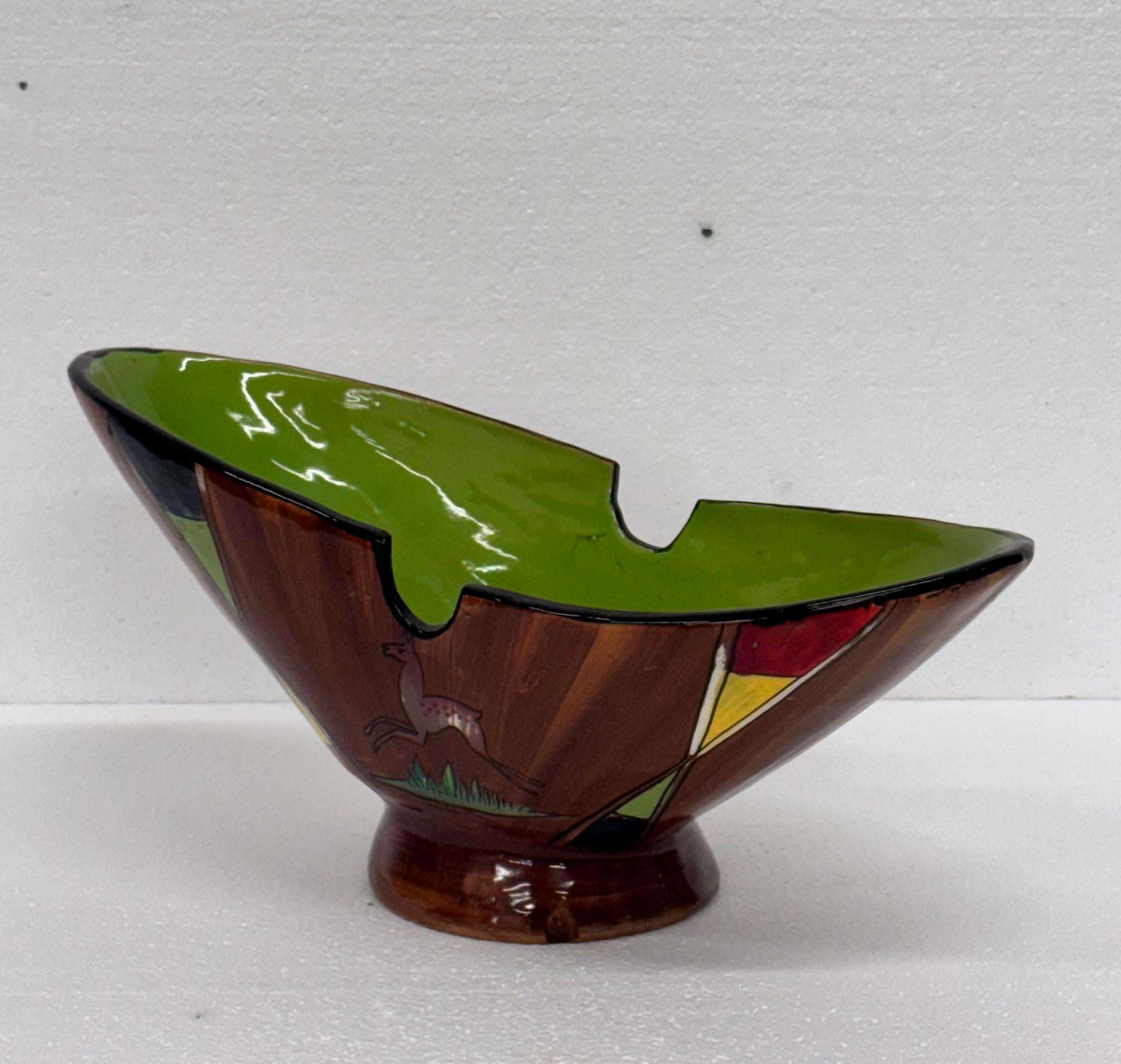 Ciotola da mensola o centrotavola in ceramica, di medie dimensioni.
Si tratta di una produzione italiana degli anni 50/60.
Il decoro, con forme geometriche ed animali, riprende alcuni dei motivi tipici del periodo.
Molto piacevole l'uso fatto dei