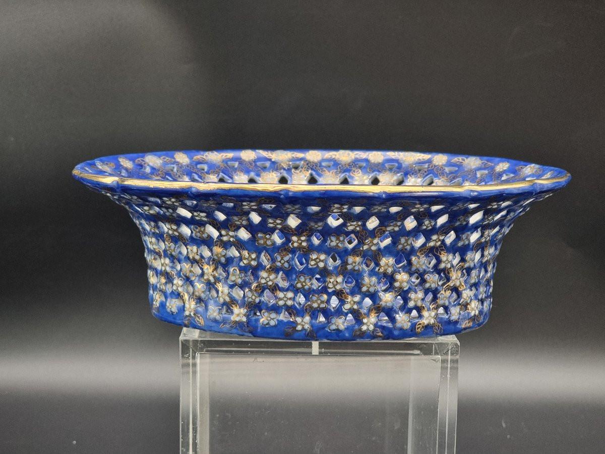 Élégante coupe ovale en porcelaine ajourée, décorée d'émail bleu cobalt et de motifs floraux raffinés et dorés. La bande perforée rappelle les décorations traditionnelles de la 