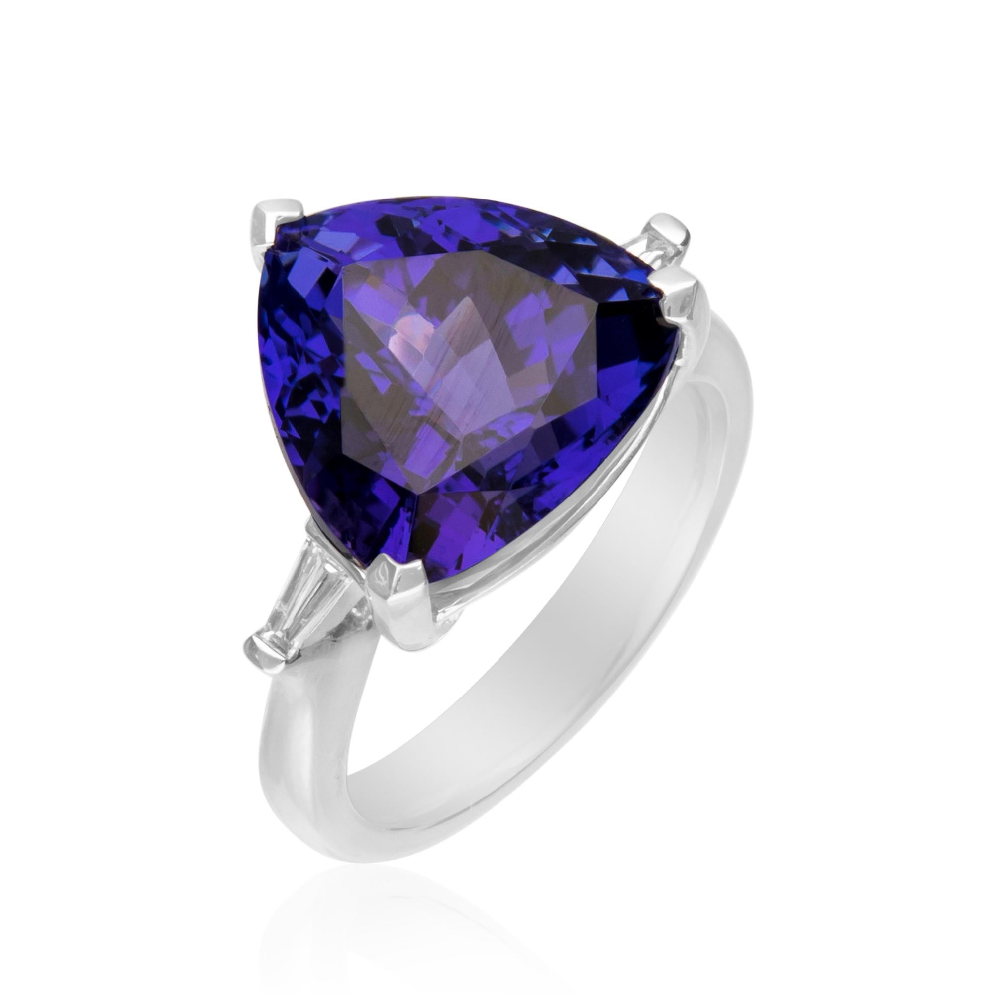 This unique designer ring is crafted in 18-karat White gold and features a trillion cut 13.26 Carat Tanzanite and 2 tapered baguette Diamonds 0.13 Ct. GH SI2 quality. This ring comes in size 7 and is a perfect gift either for yourself or someone you