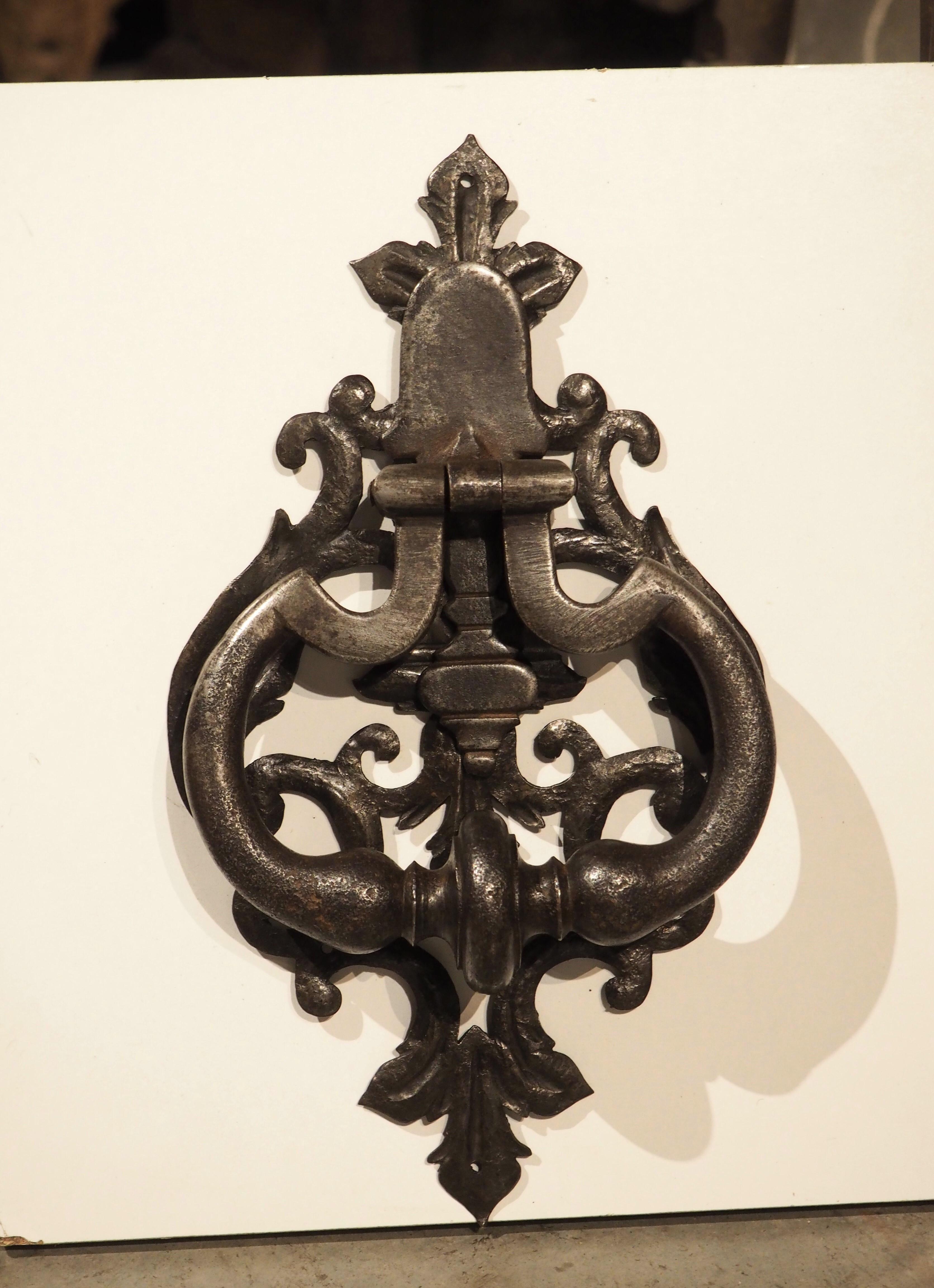 A beautiful Italian door knocker from Tuscany, Italy, the wrought iron material would pair well with a door of any color. Hand-wrought circa 1700, the foliate backplate is fronted by an ovate handle with incised upper edges, resulting in a pair of