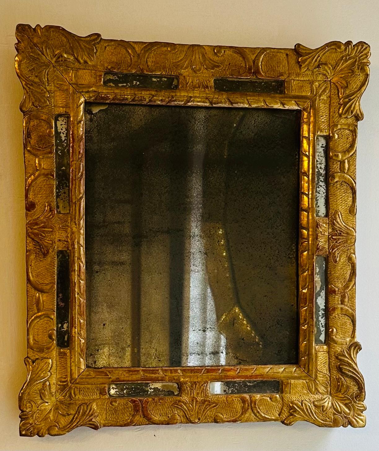 An original French mid-eighteenth century parcel gilt mirror with its original glass.  The gilded wooden frame features foliage decoration and eight cartouches of smaller rectangular mirror (two on each side) set within it to further enhance its