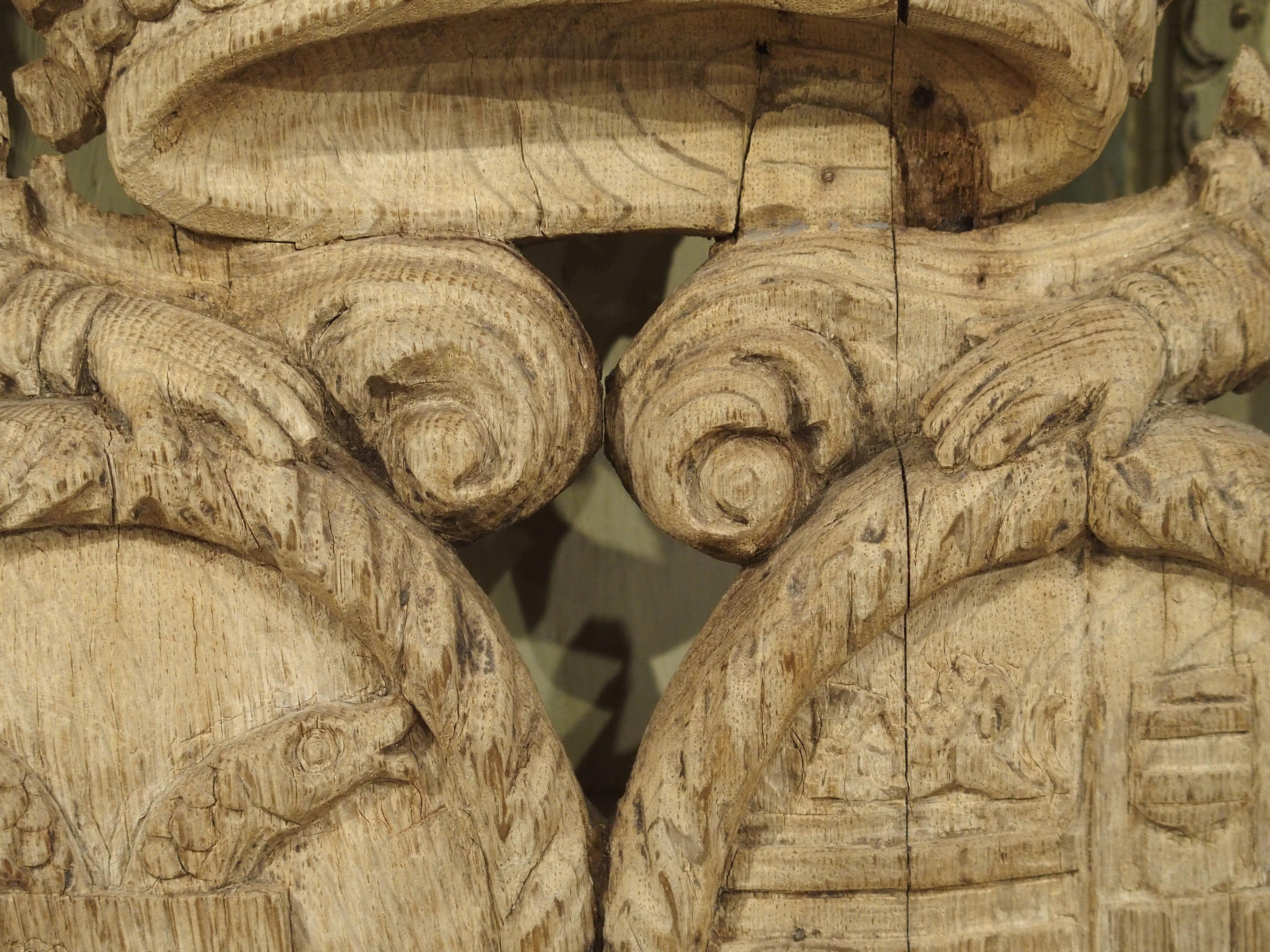 This wonderfully weathered 250-300 year old sculpture was carved in France out of Oak. It depicts two guardians flanking a noble coat of arms, surmounted by a bejeweled crown. It was most certainly part of a larger structure when originally created,