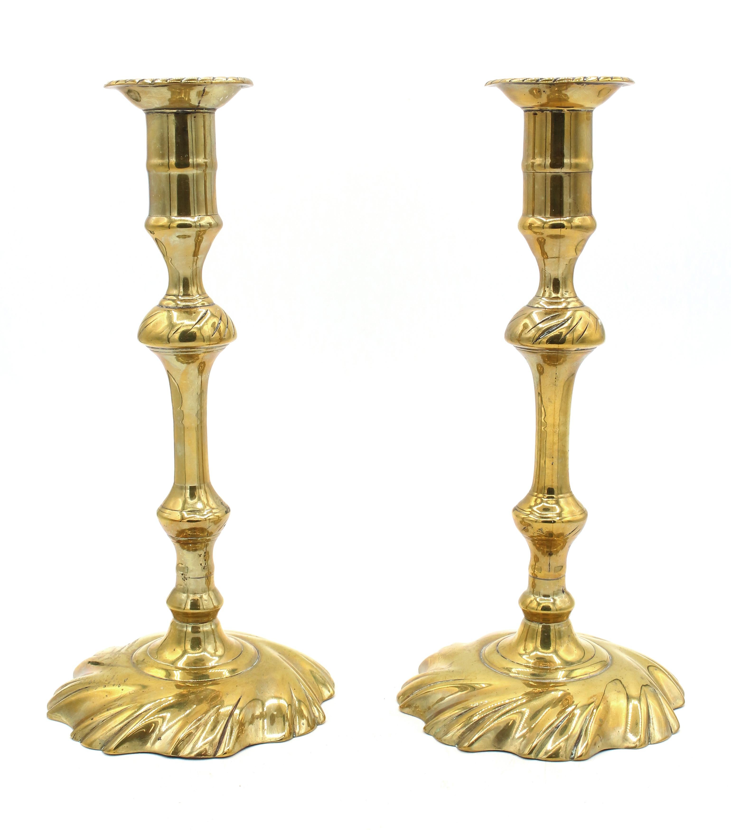 CIRCA 1750 Periodo Giorgio II Coppia di candelieri in ottone. Base a vortice; fusa in 2 parti per ogni sezione. Il pomello decorativo è anch'esso tagliato a volute che riflettono le basi, mentre i bobeches sono tagliati con un bordo gardroon. Patina