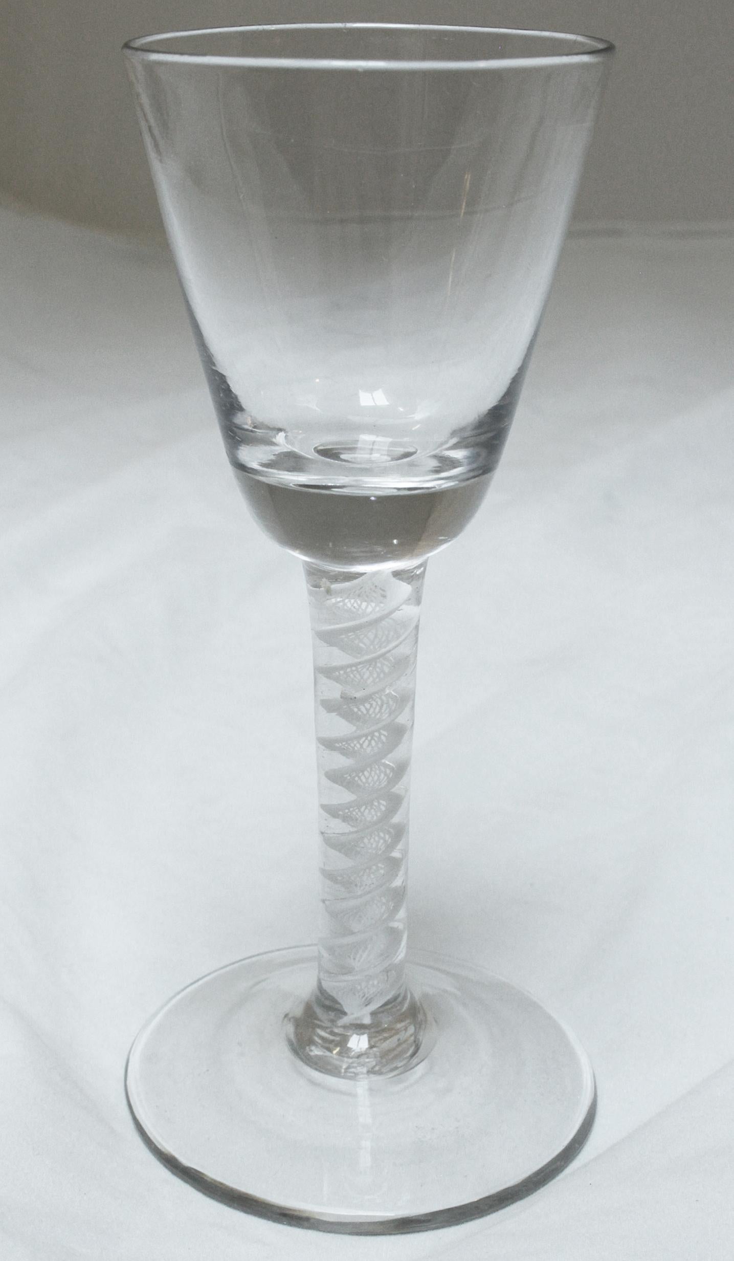 Ein feines Weinglas des Toastmasters aus dem Jahr 1765 mit trügerischem Schalenboden. Runder spitzer Trichter. Flache Basis, mehrfach breite Spiralfäden (Spitzendrehung skizziert).
6 1/2