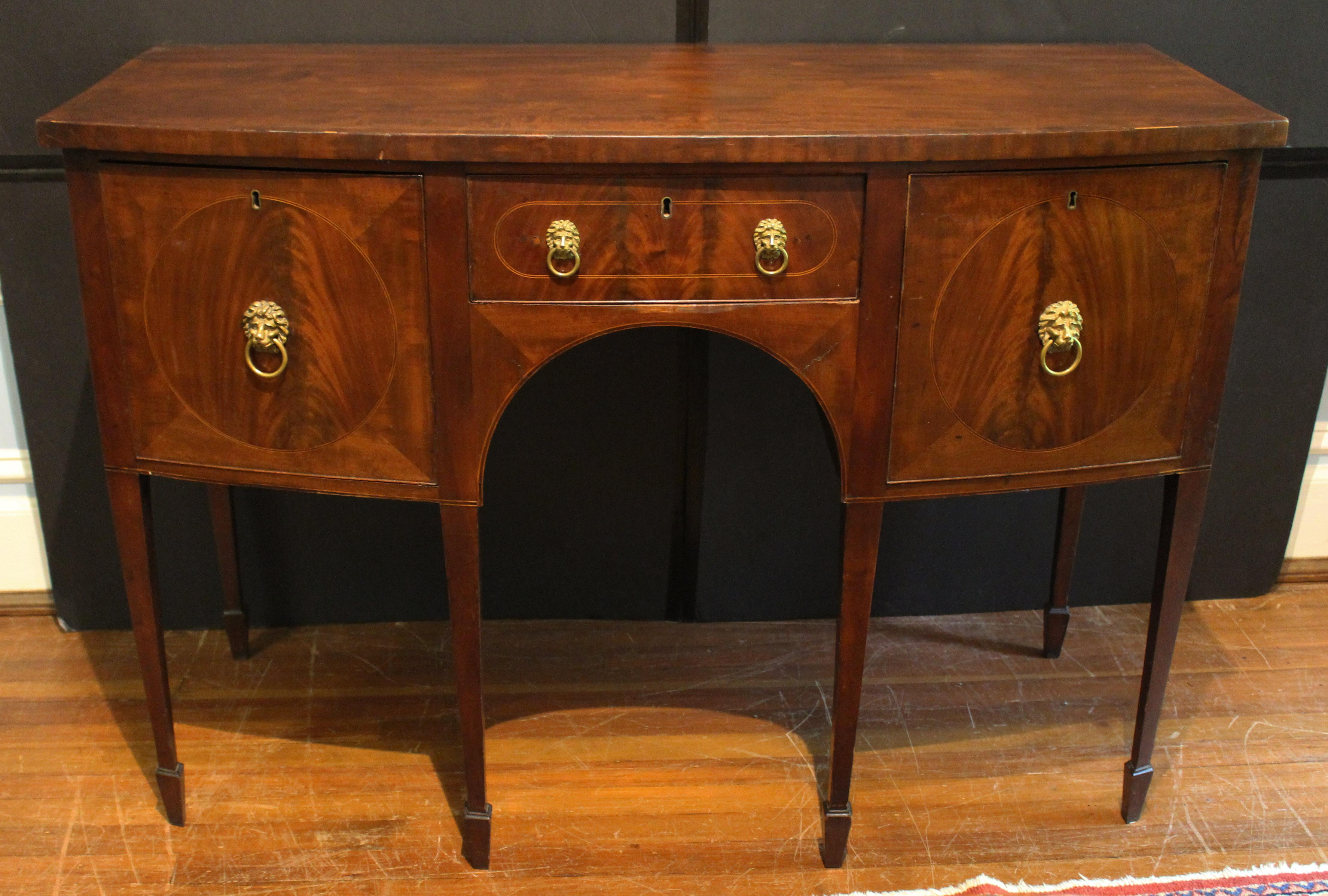 Circa 1770-90 George III small bowfront sideboard, English. Mahogany & mahogany veneers with oak secondary. Line inlays, banded top & circular flame panels distinguish this London made piece. Raised on square, tapered legs with spade feet. Deep