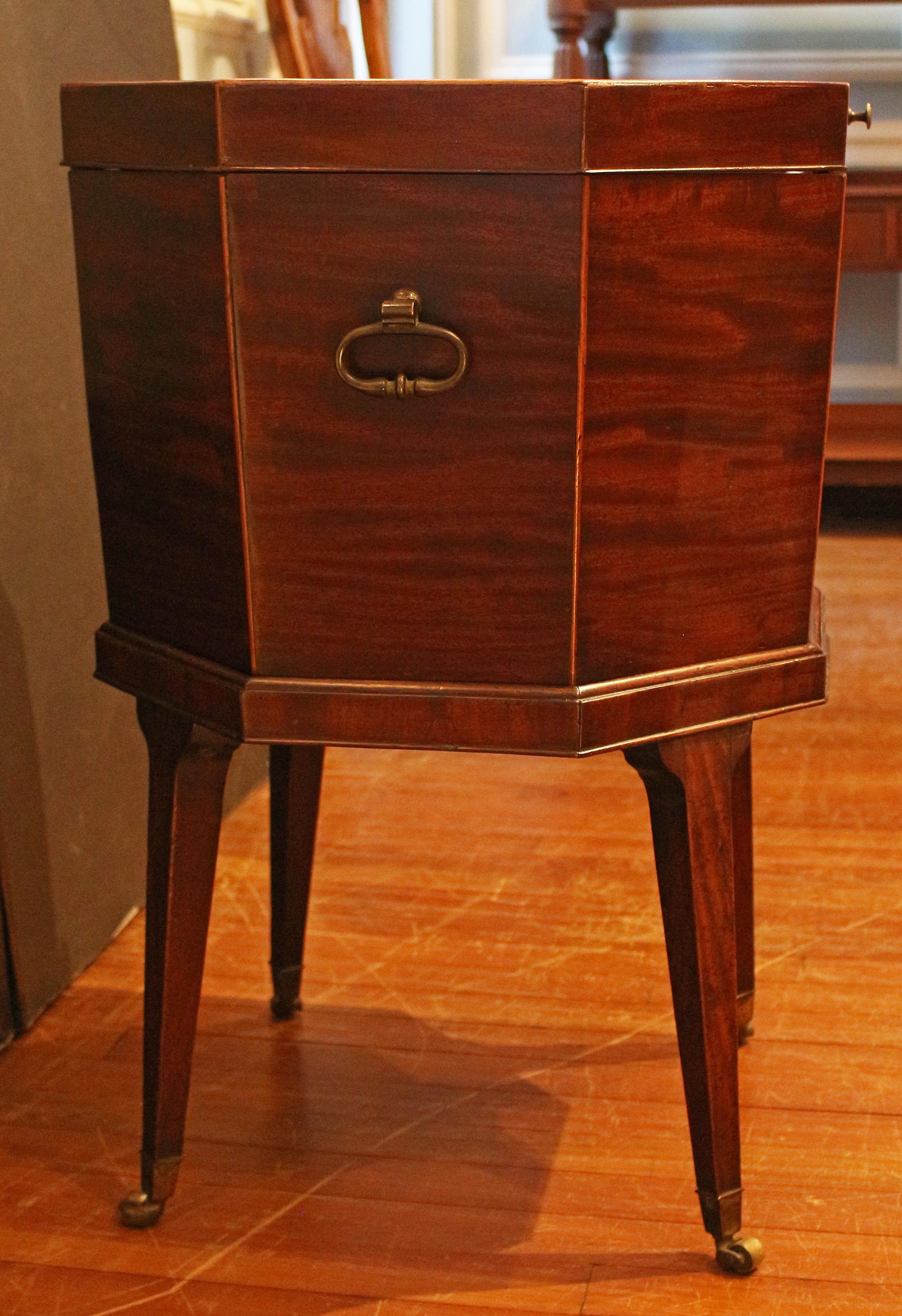 Circa 1770 George III period cellarette on stand, English. Octagonal form with molded base edge over intergral base. Solid mahogany with line inlay edging of boxwood; the top with exceptional flame grain. Raised on original stand with tapered legs,