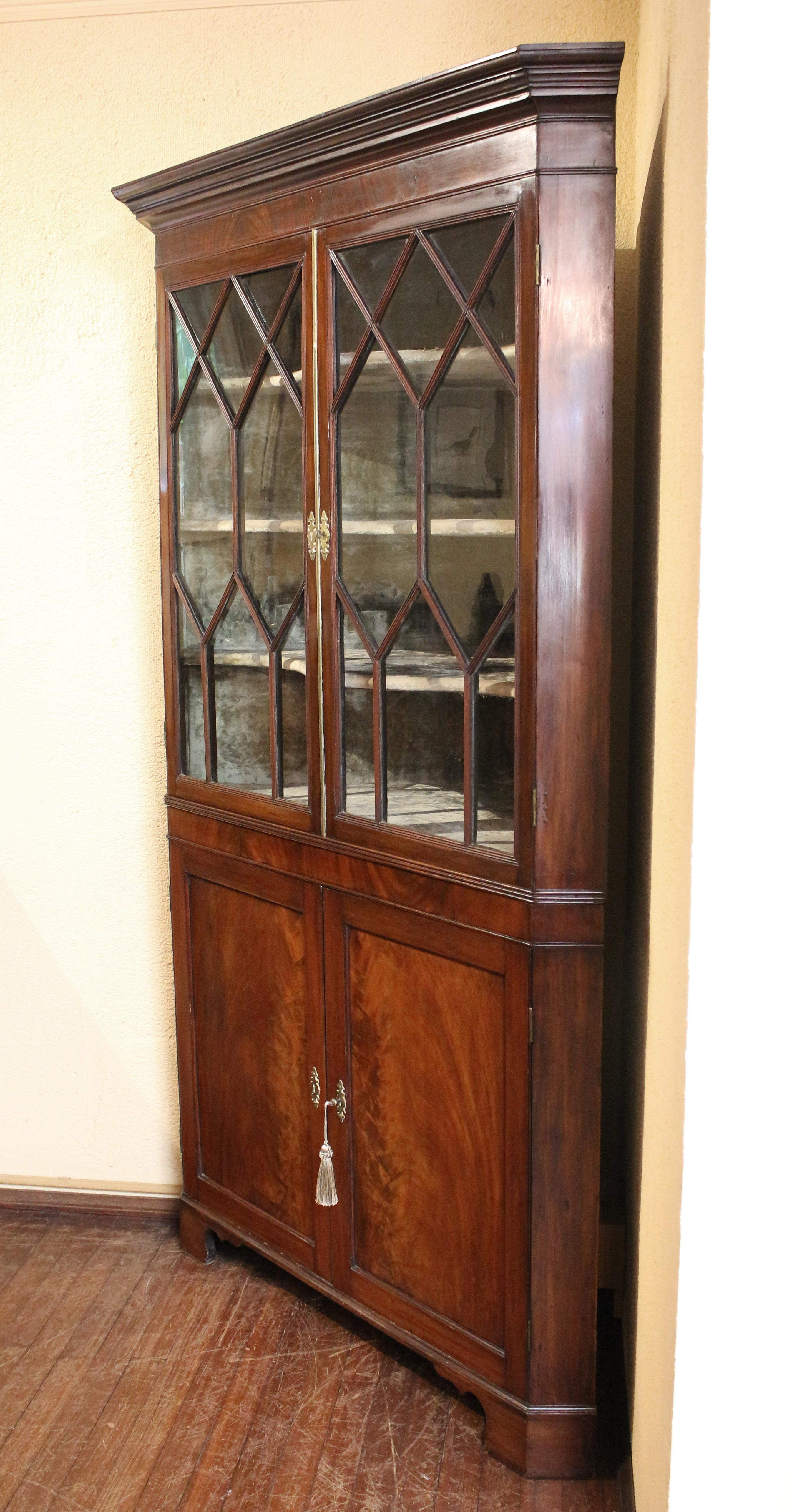 Circa 1780-1800 George III corner cabinet, English. Mahogany. A handsome example with reeded astragal diamond glazed upper doors & flat paneled lower doors. Well figured flame mahogany veneers used to great visual effect. Velvet lined interior upper