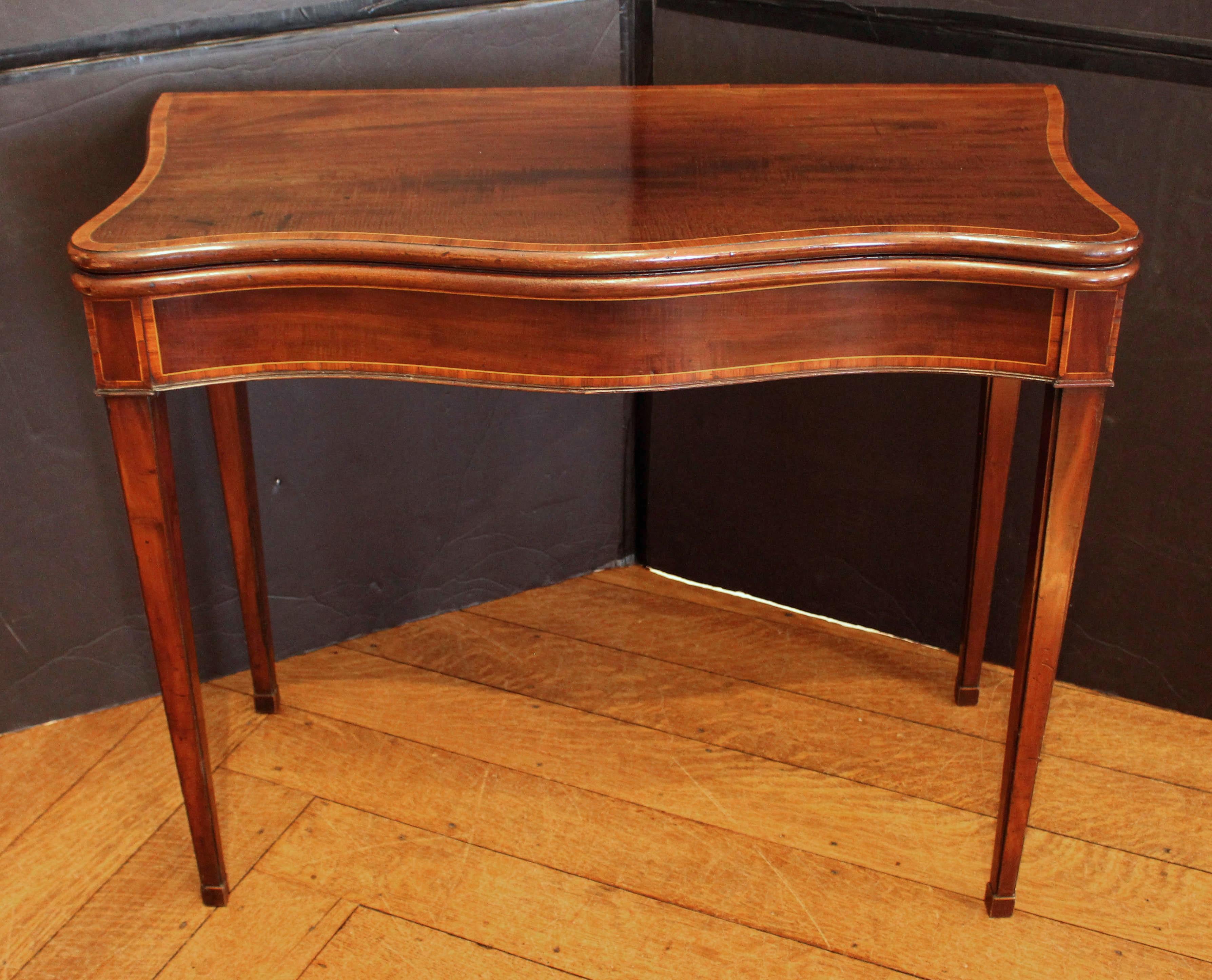 Circa 1780 George III serpentine form games table, English. Solid mahogany timber richly embellished with kingwood crossbanding on all top surfaces & on the apron, offset by satinwood stringing. Bullnose molding. Straight, tapered legs, ending in