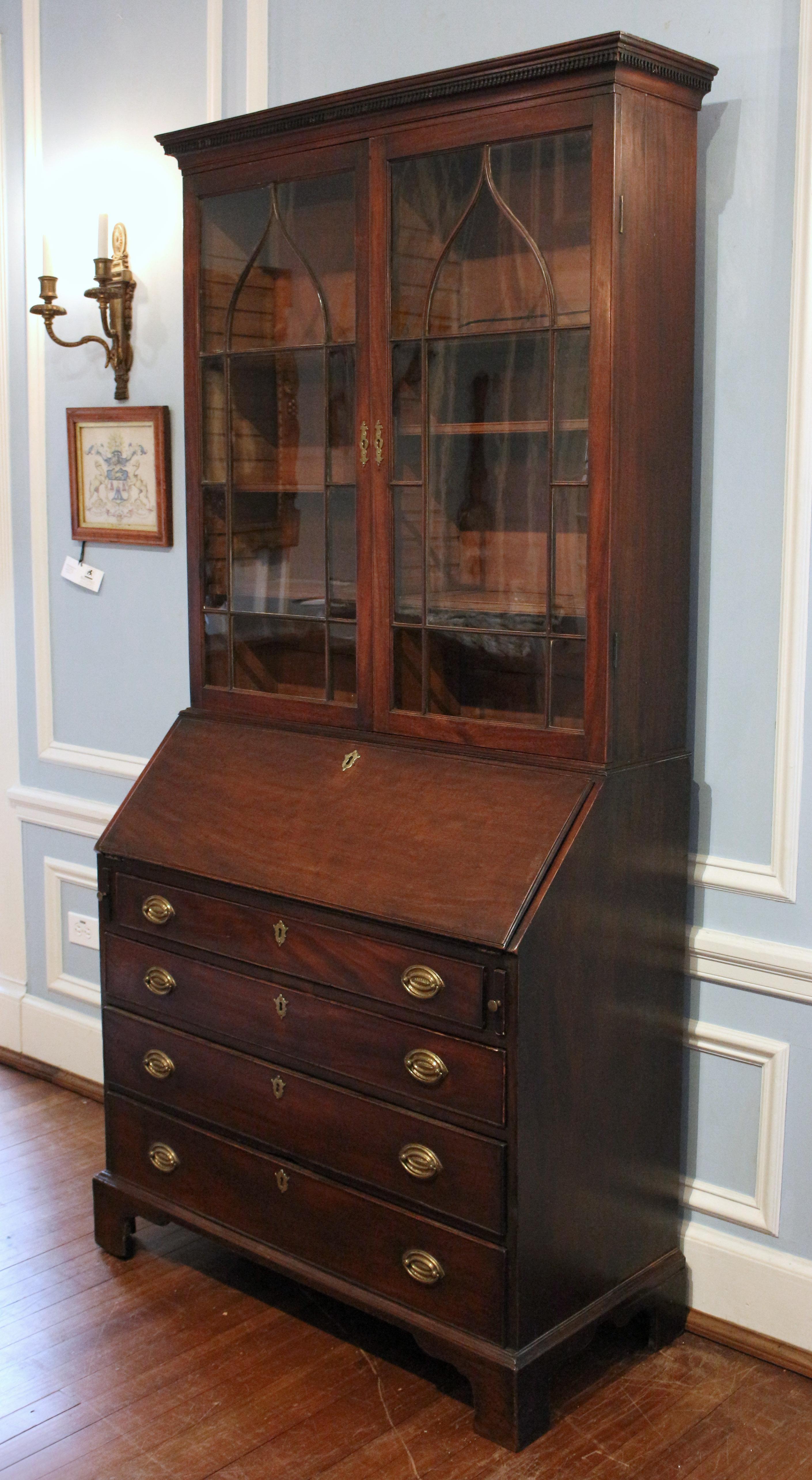 Circa 1780 George III period bureau bookcase, English. Mahogany with Gothic arched glazing (crack in one lower pane). The bookcase is divided with adjustable shelves on each side. Dentil molded crown (some 