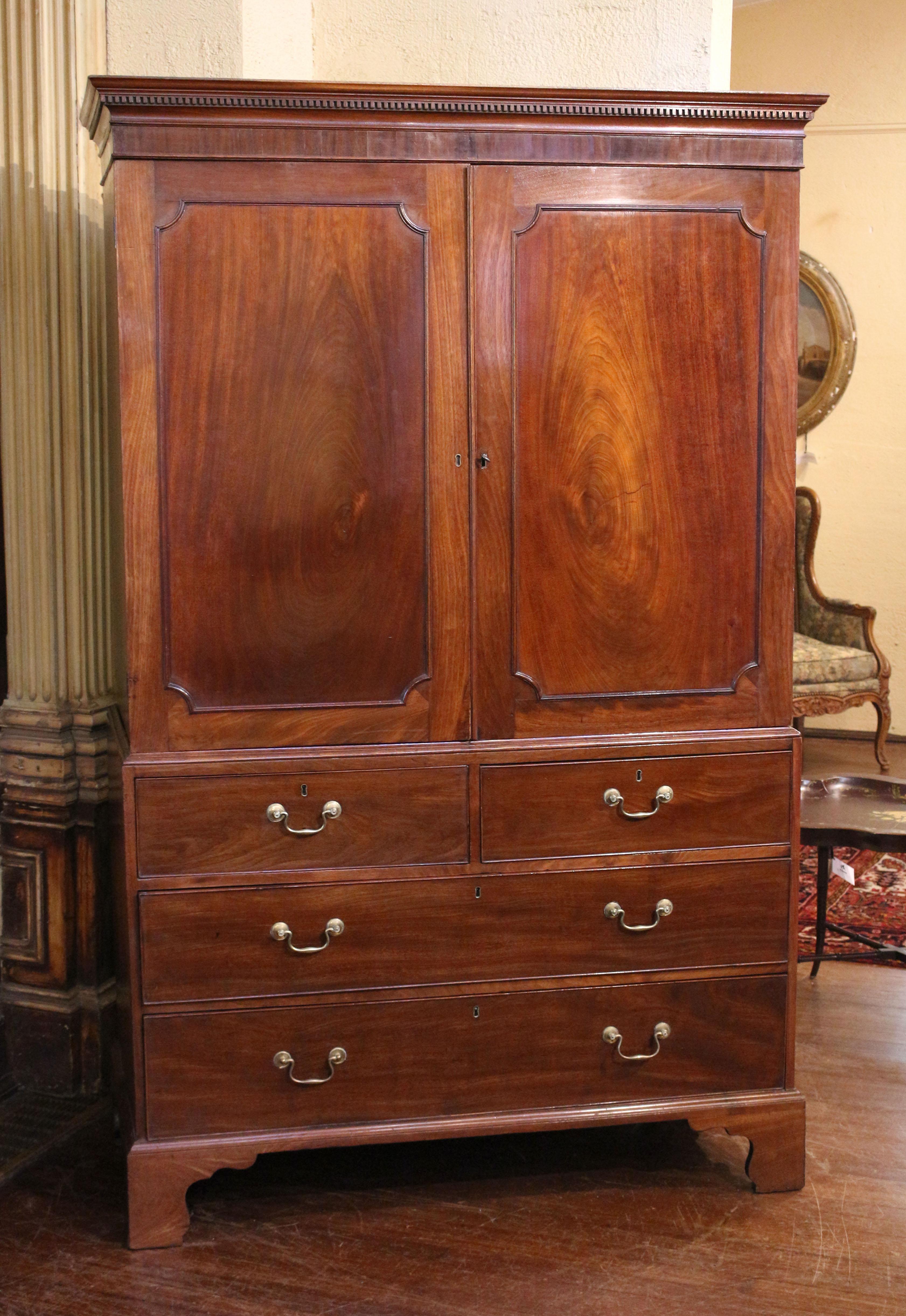 Circa 1780 George III period linen press, English. Cavetto corner molded doors enclosing a rank of 5 linen slides over 2 short over 2 long drawers raised on bold, shaped bracket feet. The whole surmounted by a dentil molded crown. Mahogany with oak