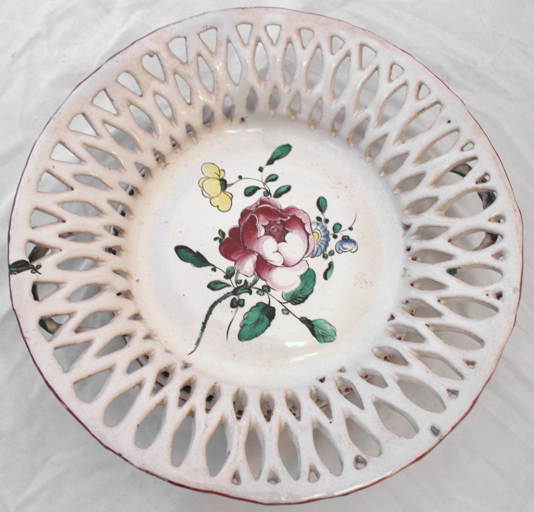 Circa 1780 Cesto neoclásico de loza reticulada de Luneville con la típica reserva central de aerosol floral y borde rosa, el enrejado exterior salpicado de ramilletes rosas y amarillos. Observa las asas entrelazadas de vid verde y la encantadora