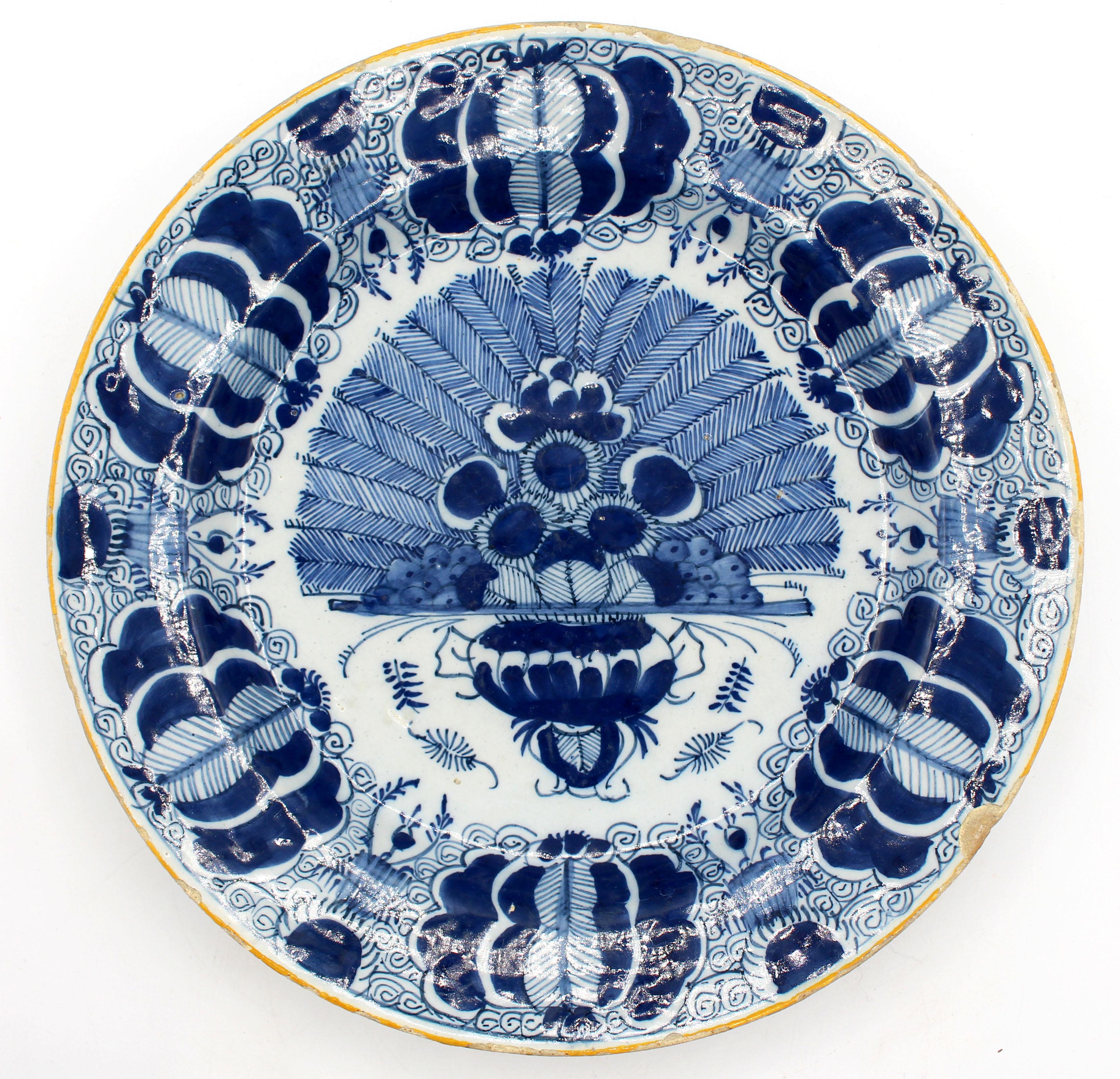 Circa 1780 pair of Delft blue & white large chop plates or chargers. Centered on reserves of peacock feathers made by & marked by De Klaauw (The Claw) factory. Yellow rim. Rim frits, a rim chip & one very old base rim chip. 12 5/8