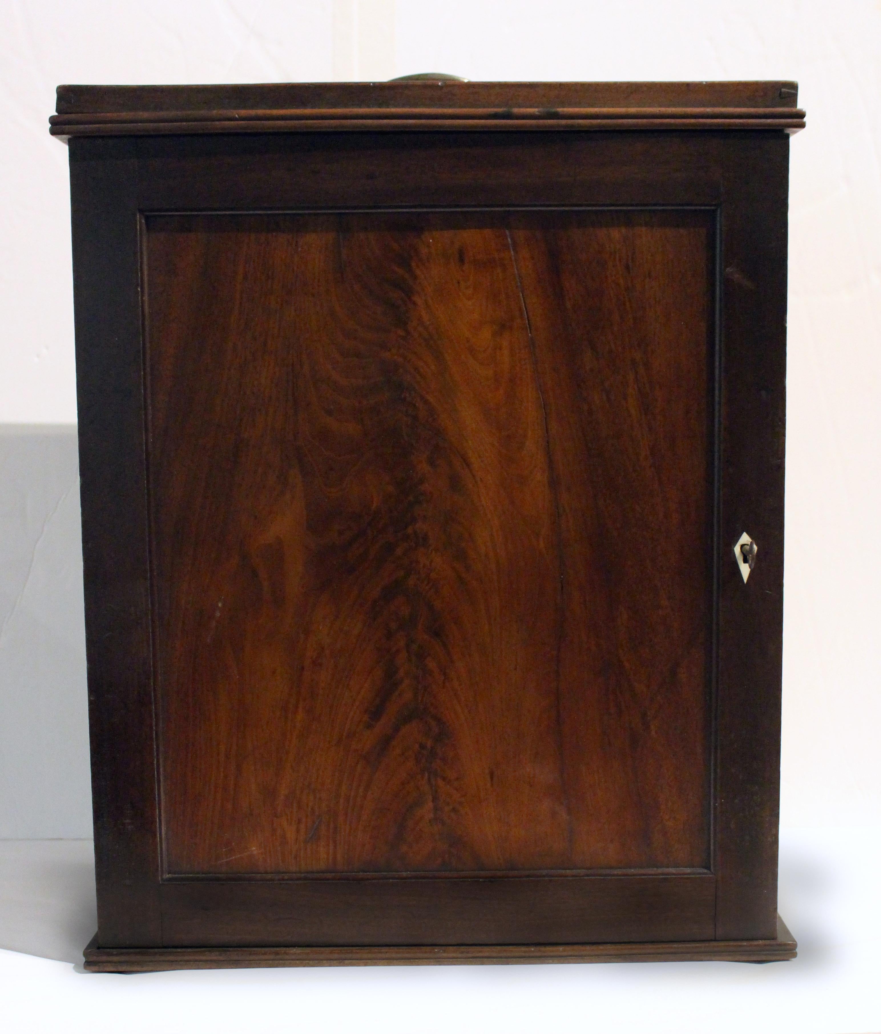 Circa 1780 small Georgian portable table-top cabinet box. Flame mahogany door. Robust brass bail & rosette handle on galleried top. Four interior shelves. Designed for unknown purpose. Could be used as a small end table for a chair. 17 1/8