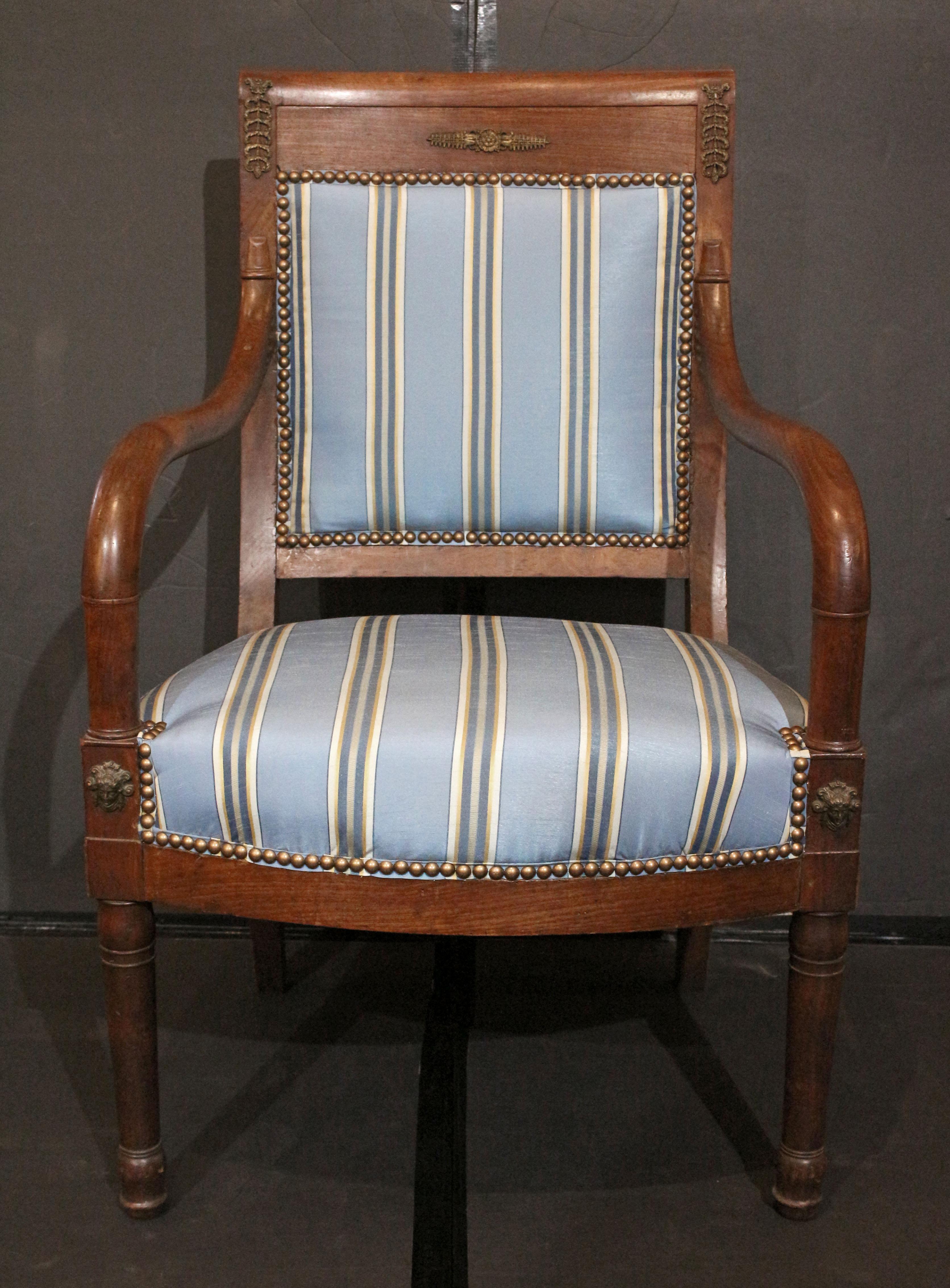 Circa 1800-1815 fauteuil or open arm chair, French. Mahogany. Directoire to Empire period & style. Brass mounts. Turned, tapered legs with ring turned carving. Newly upholstered in a blue silk fabric with stripes.
23.25