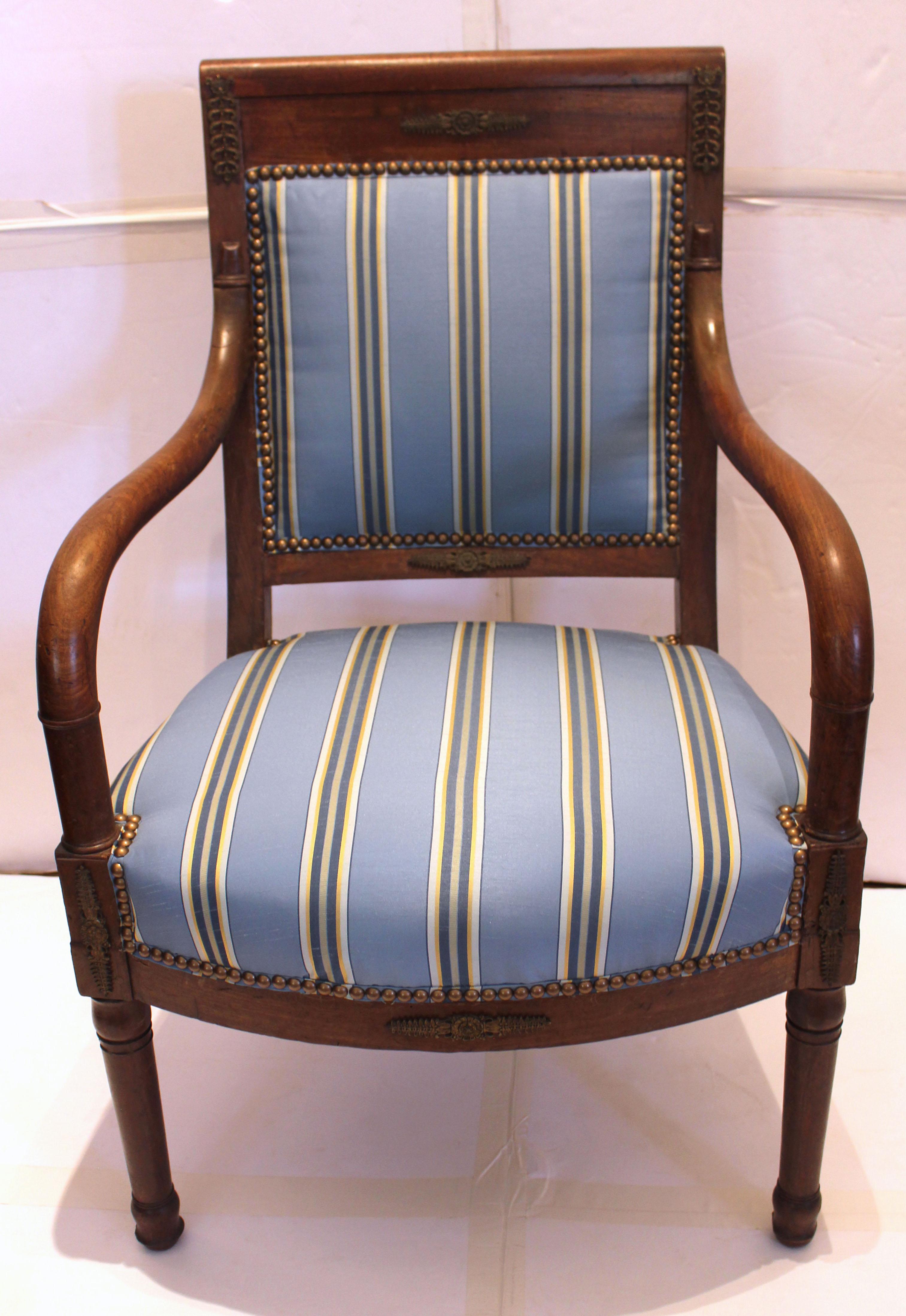 Circa 1800-1815 pair of fauteuils or open arm chairs, French. Mahogany. Directoire to Empire period & style. Brass mounts. Turned, tapered legs with ring turned carving. Old repair to one upper arm. Newly upholstered in a blue silk fabric with