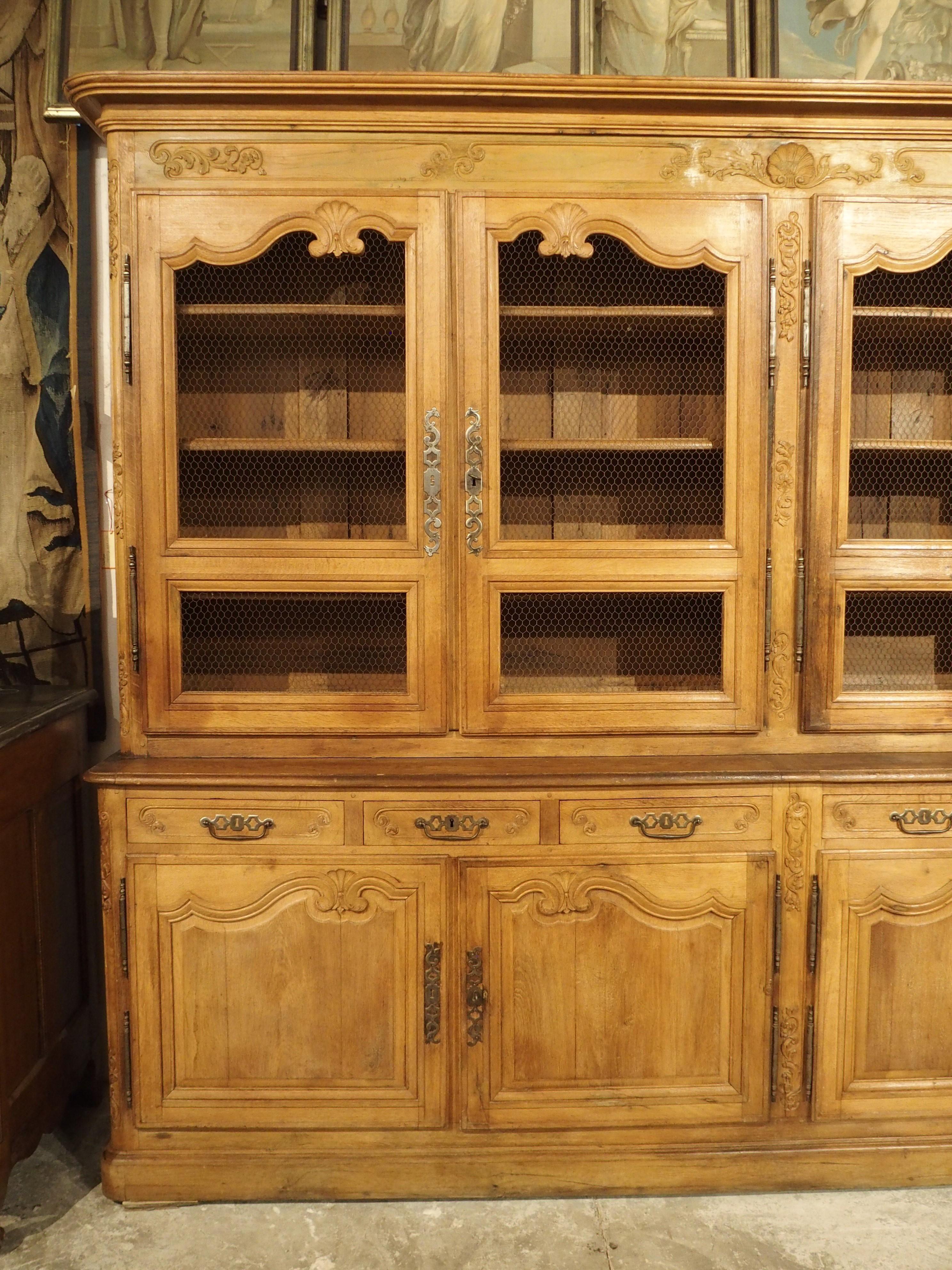 An unusual double bibliothèque from southwest France, this impressive bookcase was hand-carved from oak, circa 1800. Several layers of molding adorn the crown, including a deep cavetto cornice above a wonderfully carved frieze with a scalloped shell
