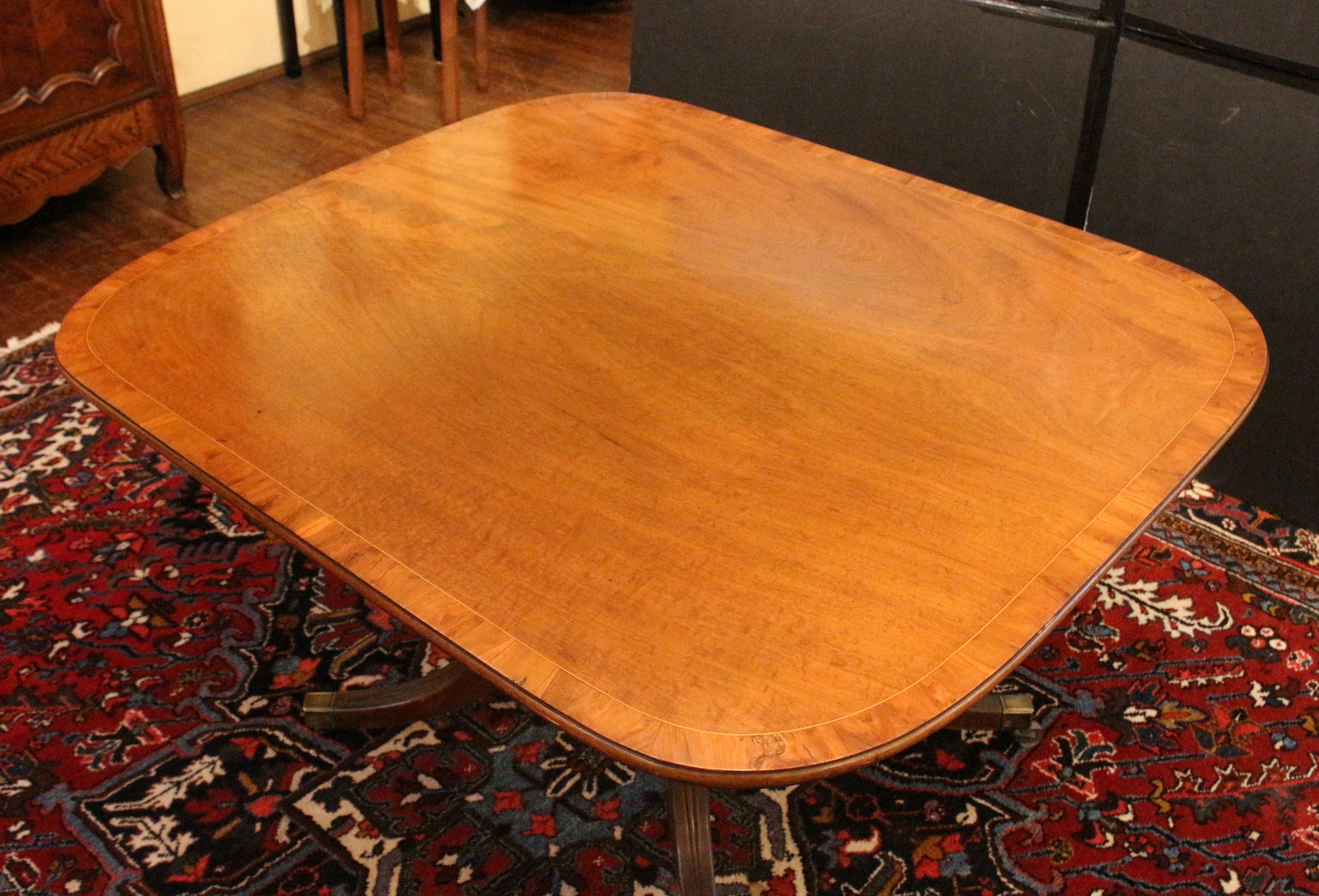 Circa 1800 Georgian tilt-top breakfast table or center table, English. Well figured mahogany cross-banded with yew wood set off by boxwood stringing; molded edge. Sturdy pedestal with well turned upright and 4 outswept, elegantly reeded legs ending