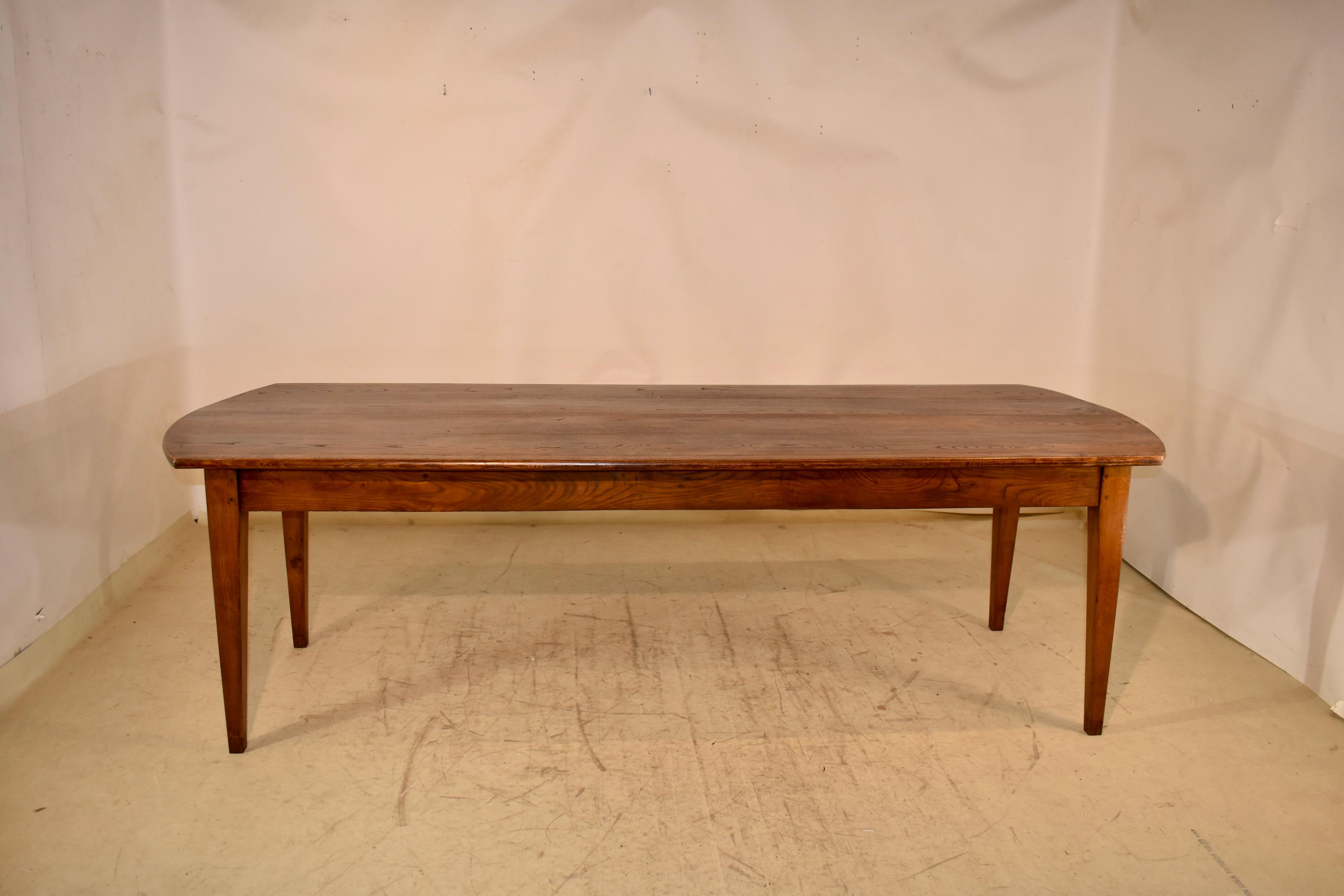 Early 19th century long farm table from France made from chestnut.  The table has a wonderfully grained top with lovely curved ends which gives a fabulous overhang on each end.  The patina on this table is honest and well-earned.  The top follows