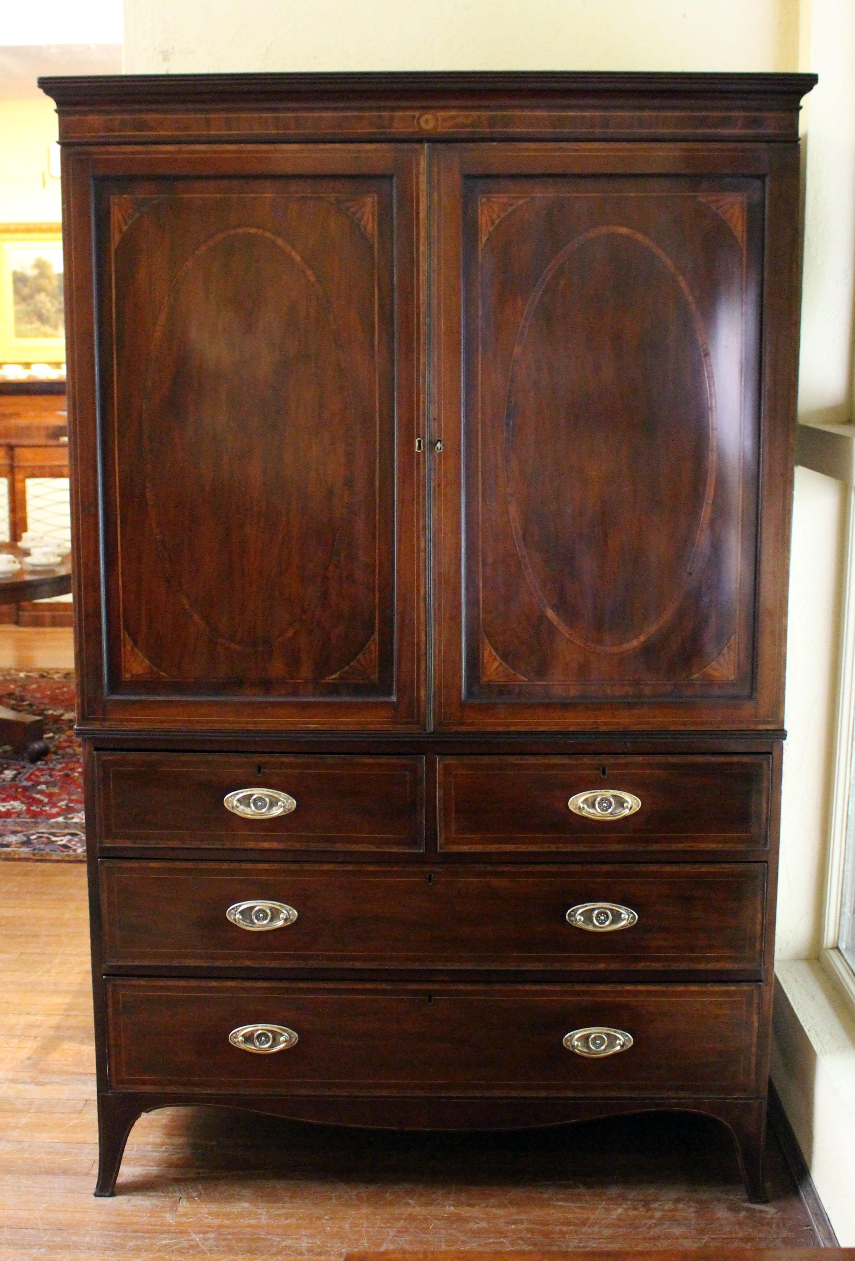 Circa 1800 Georgian period inlaid linen press, English. Mahogany with extensive inlays including large ovals with rectangular borders and spandrel corners on the doors. Mahogany with oak secondary wood. Reeded top crown molding with central rosette