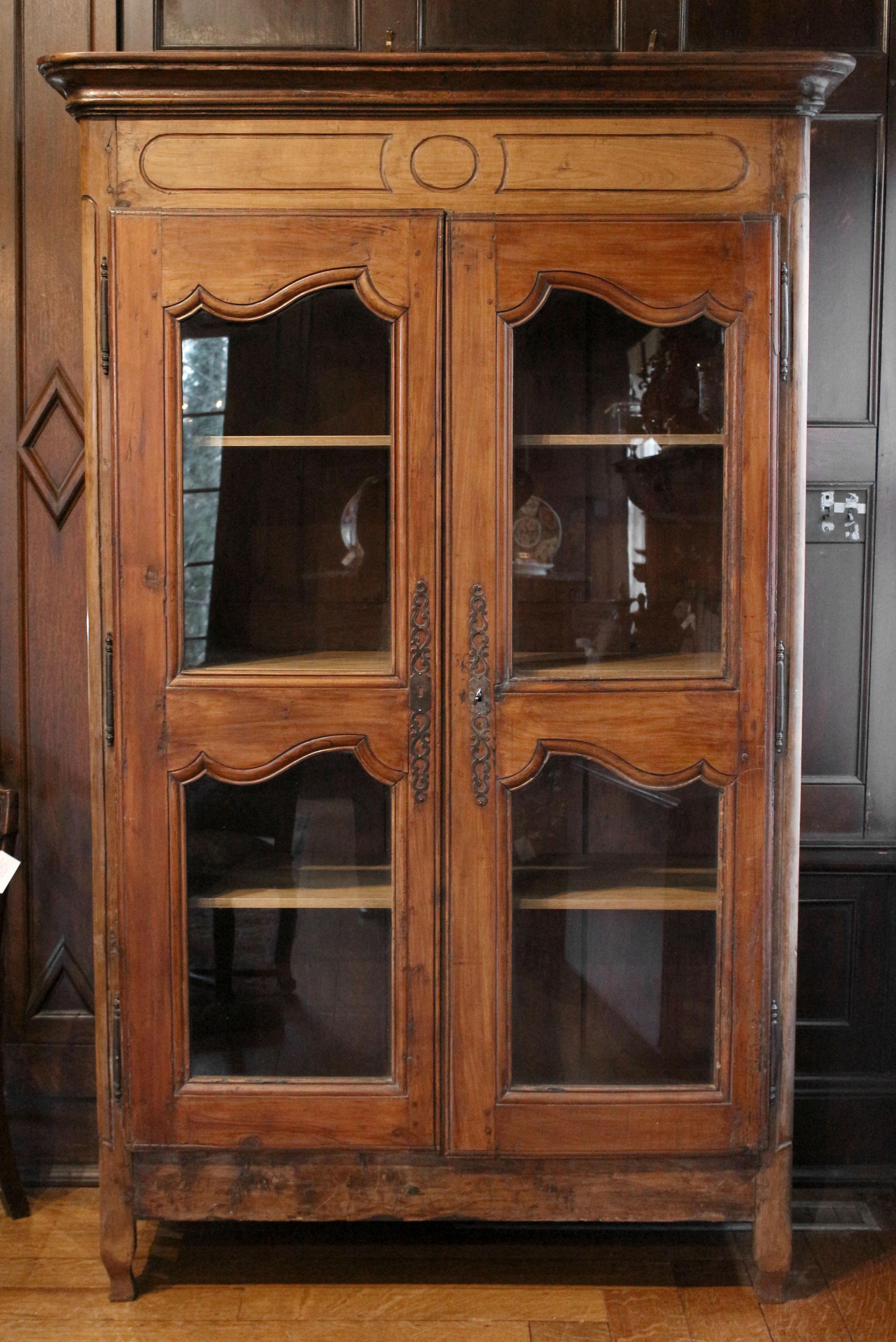 An armoire bibliotheque, Normandy, France, circa 1800. The original wooden door panels replaced with glazing to make it a bibiotheque or display cabinet form. Sides of five floating rectangular panels. Charming in its simplicity. Replaced poplar