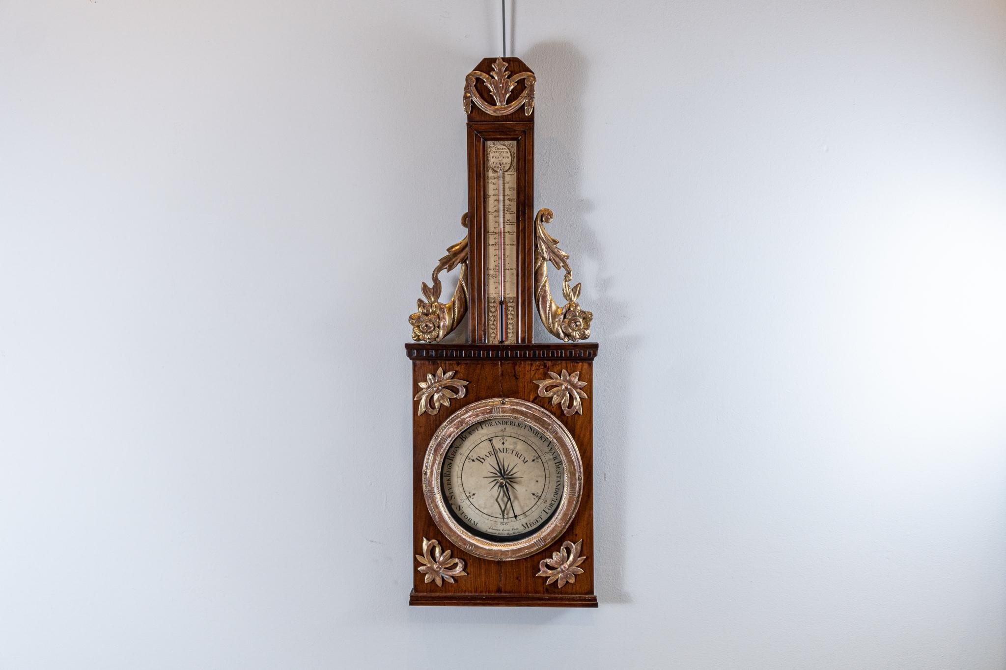 A highly decorative Swedish Gustavian barometer dating from the 1800s by Iohannes Lerra.

The dial sits centrally in a mahogany wood frame with applied gilded scrolled leaf decoration to the four corners.

The thermometer tube has delightful