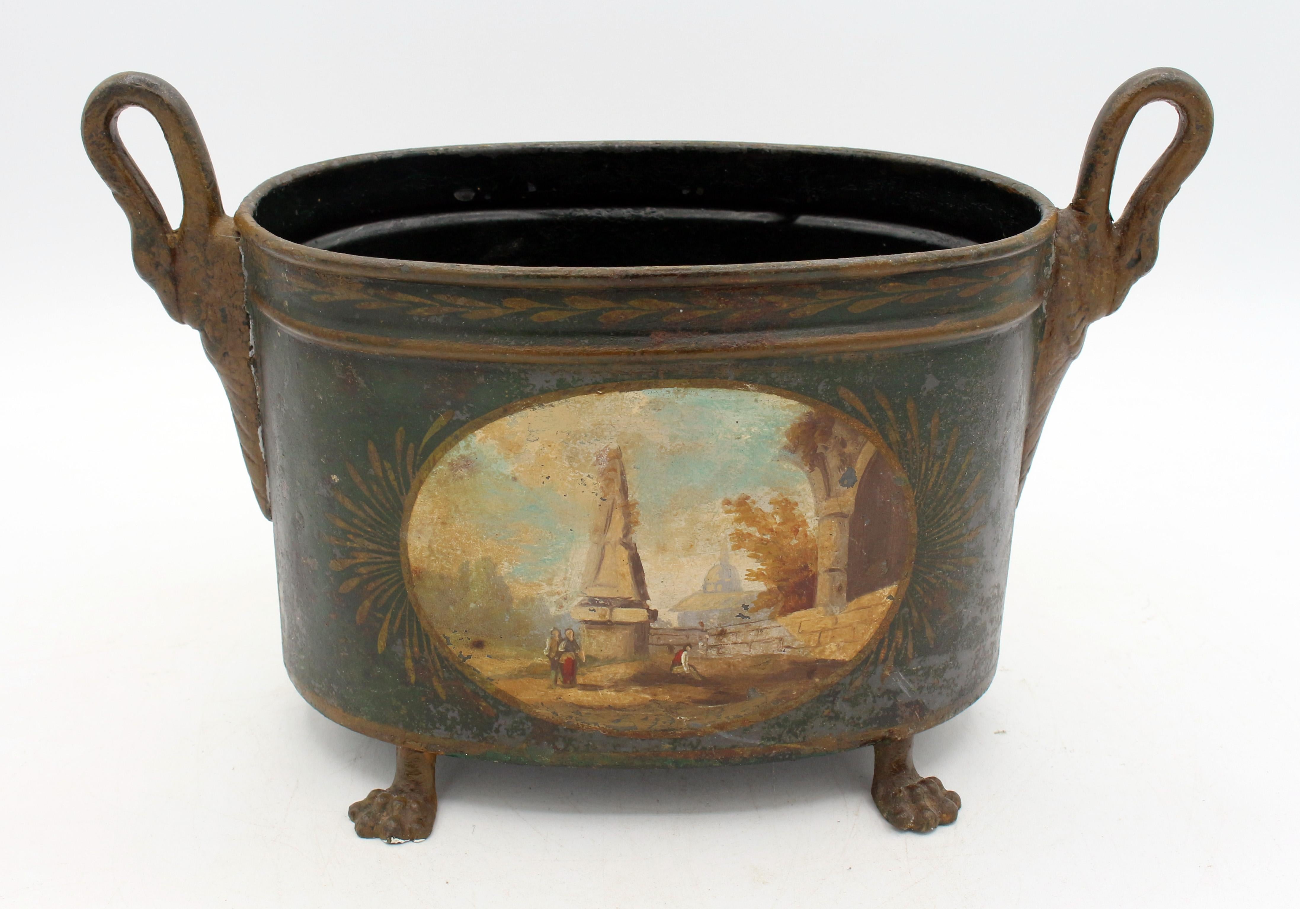 Cachepot o jardiniere ovale in tole francese del 1815 circa. Eleganza, sollevato su piedi a zampa di leone in bronzo dipinto; maniglie a cigno. Ogni lato è dipinto a mano con riserve ovali di rovine e persone classiche. Terra blu-verde. Superficie