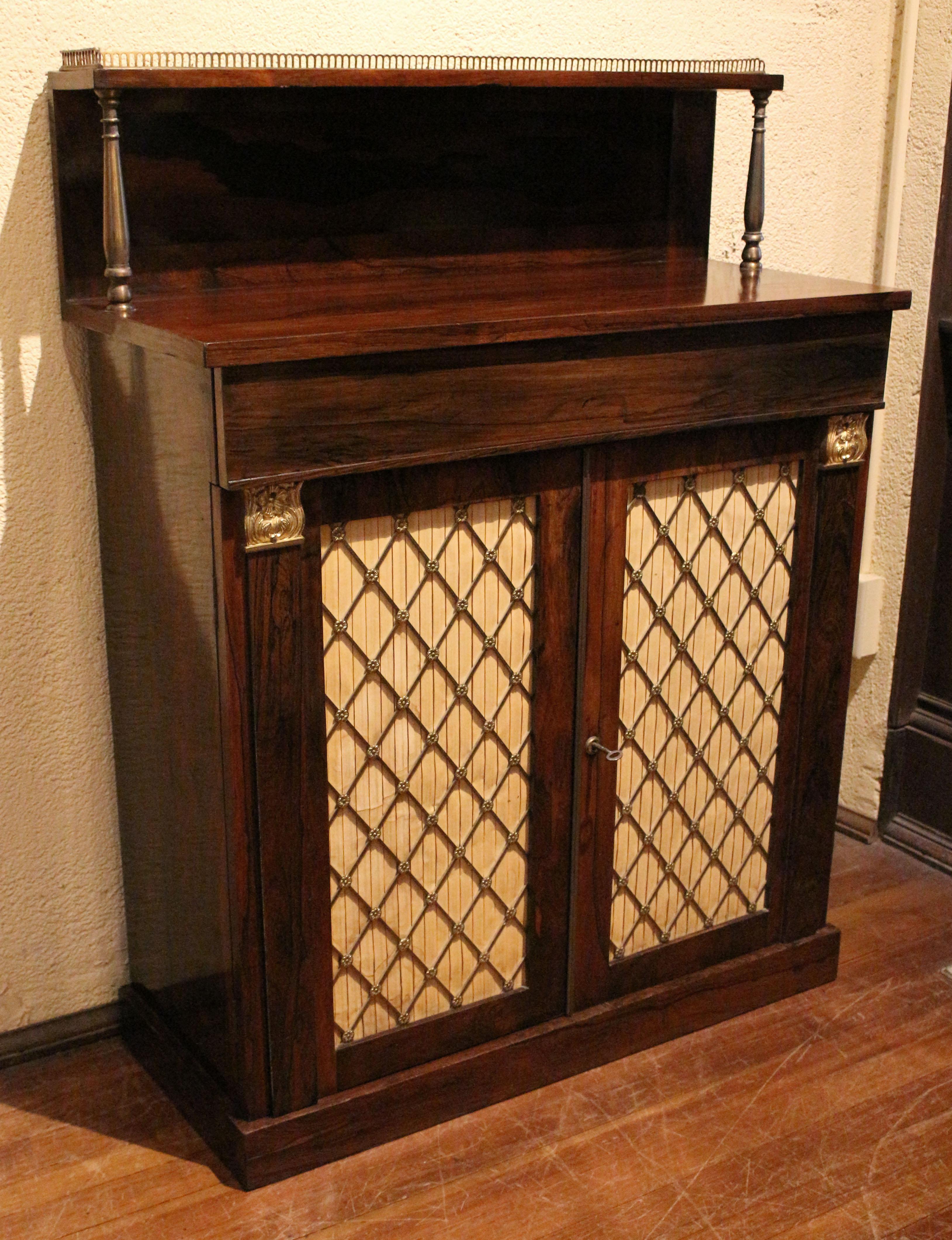 Circa 1815 Regency period chiffonier, English. Rosewood with oak secondary wood. Brass upper gallery edge, well turned brass supports for the upper tier and brass grillwork for the double doors finished with a brass molded edge & Bramah lock.